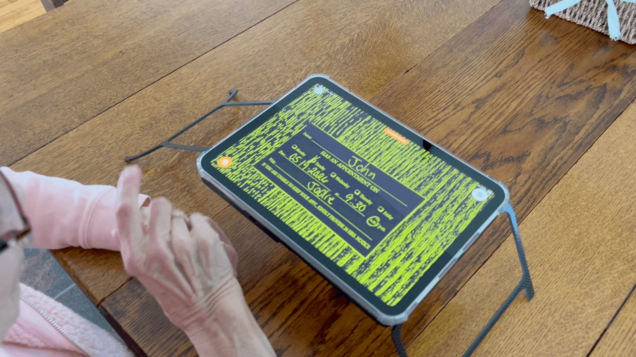 Case for Vision Solaris magnifies an appointment card on a wooden table using black-on-yellow high-contrast mode.