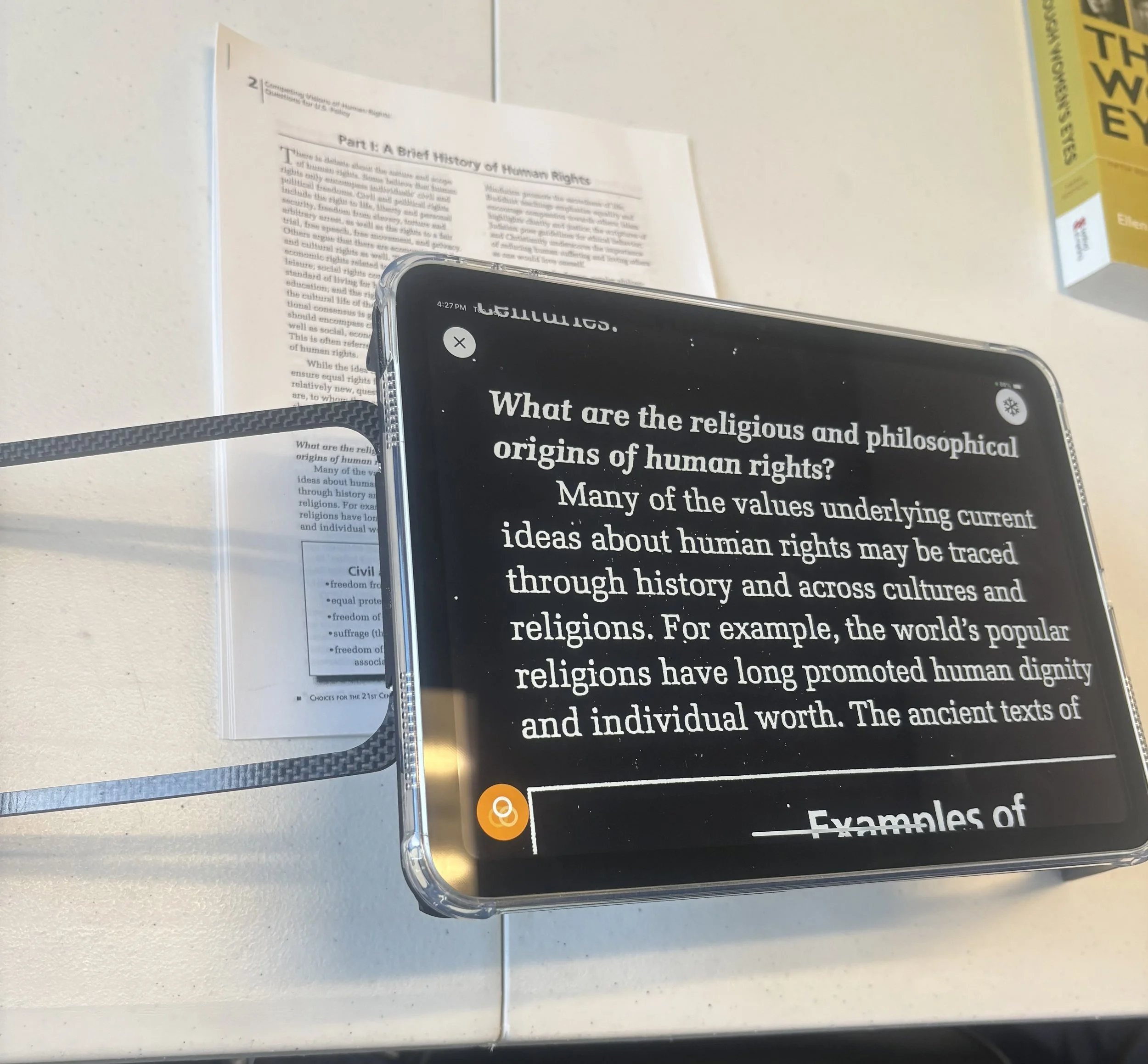 Case for Vision for iPad standing on a table with an iPad mounted on top of it, magnifying a worksheet below in inverted color mode with white text on a black background.