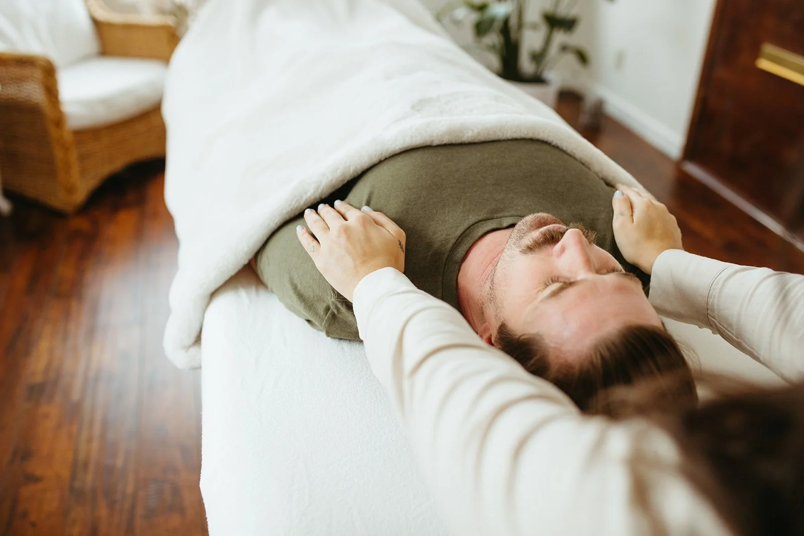 Stephanie Kamille is giving Reiki energy healing to a man on a massage table