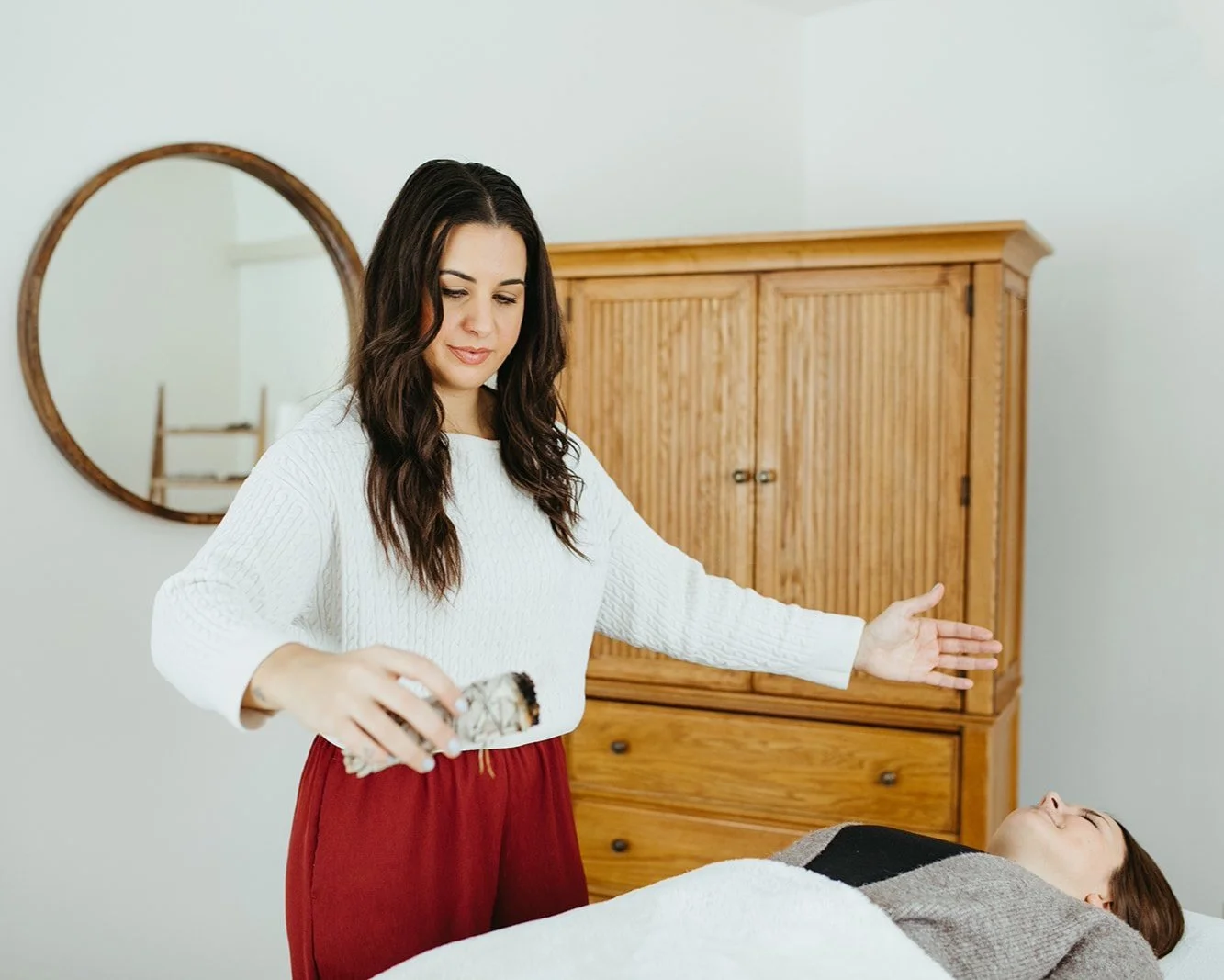 Stephanie Kamille is clearing a client on a massage table with sage