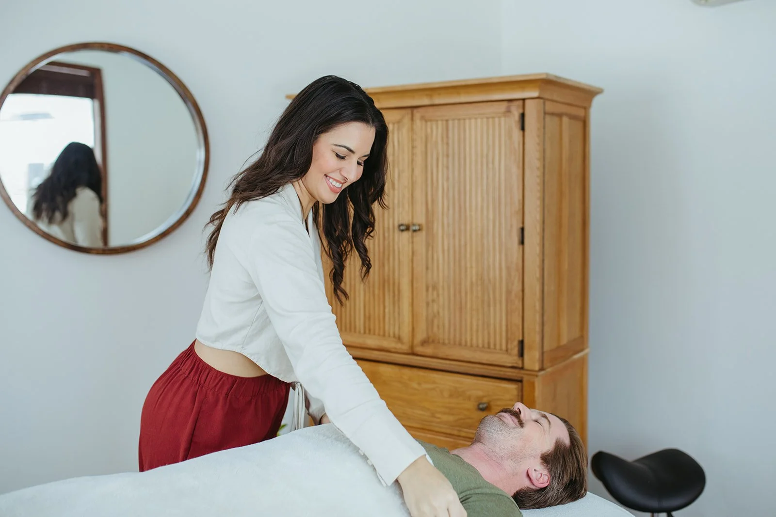 Stephanie Kamille is lifting blanket over Reiki client on massage table