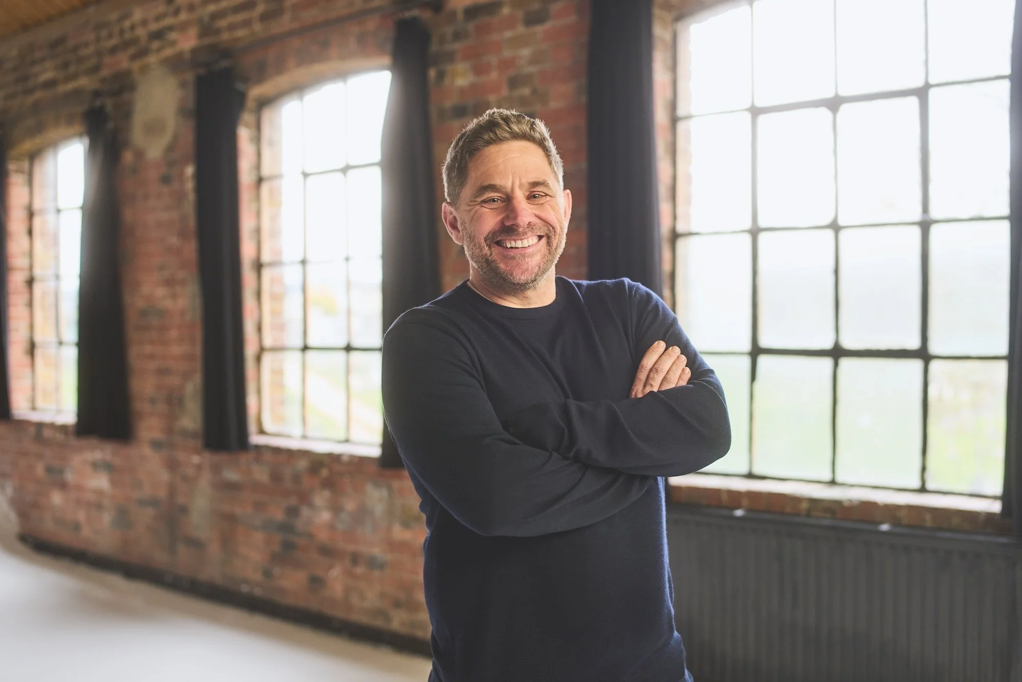 Man standing in front of bare brick wall with windows