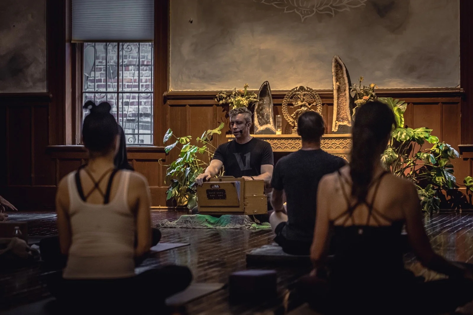 People participating in a yoga class in a room with stained glass windows and wooden paneling.