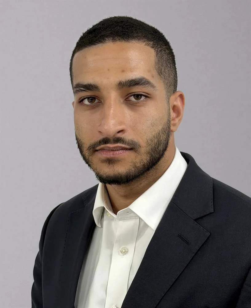 Black and white portrait of a man with short hair and a beard, wearing a collared shirt, looking slightly upward to his right.