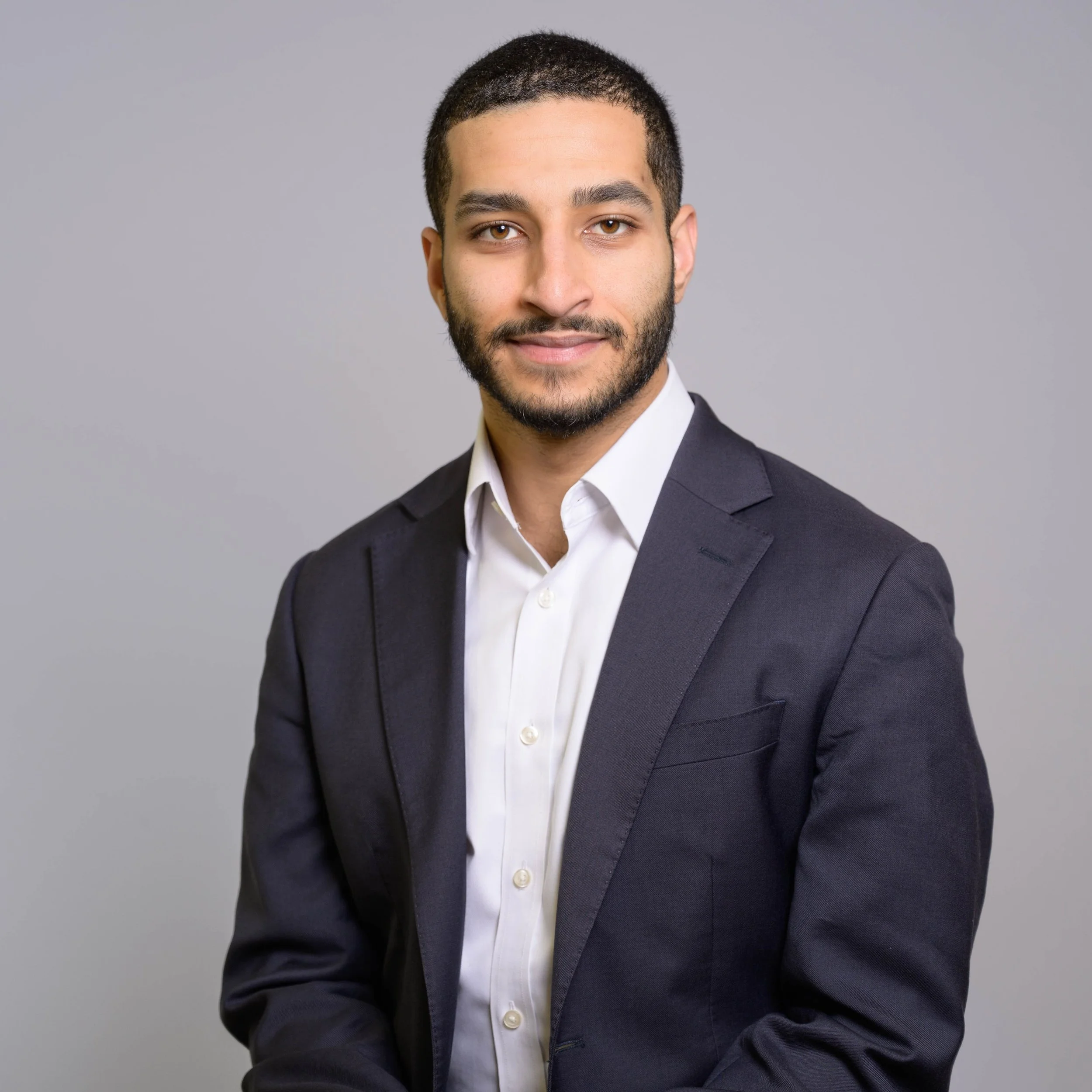Black and white portrait of a man with short hair and a beard, wearing a collared shirt, looking slightly upward to his right.