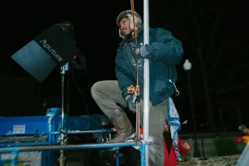 Cliff Daniels adjust a rig at night, wearing a hat and warm clothing.
