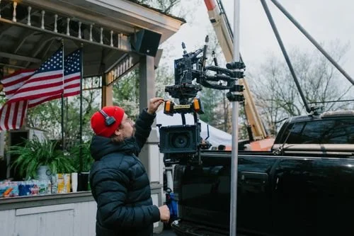 Filming scene with a blackarm rig, crew member adjusting equipment, at Silver Dollar City.