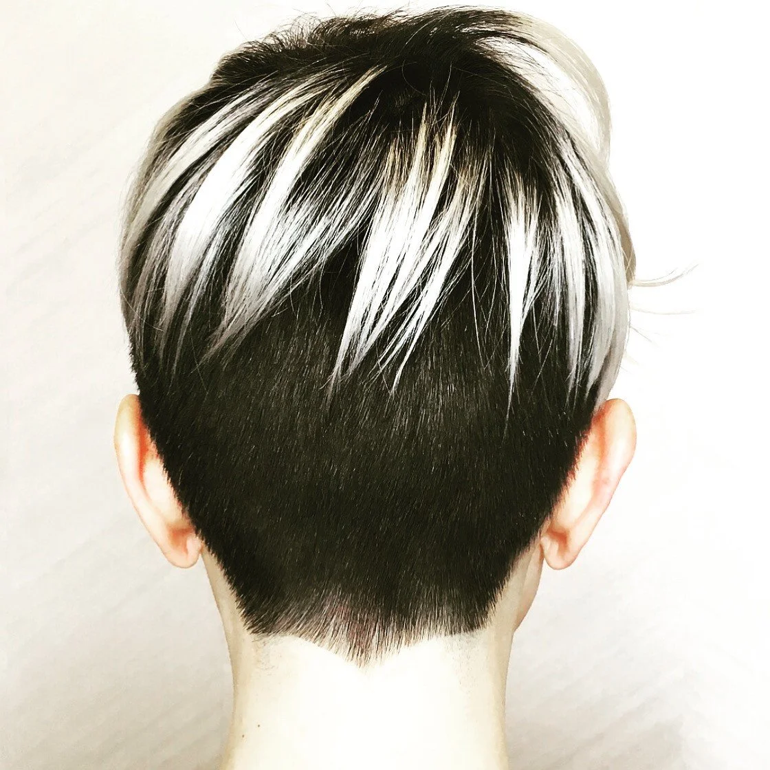 Women's short haircut with tapered back and blonde accents