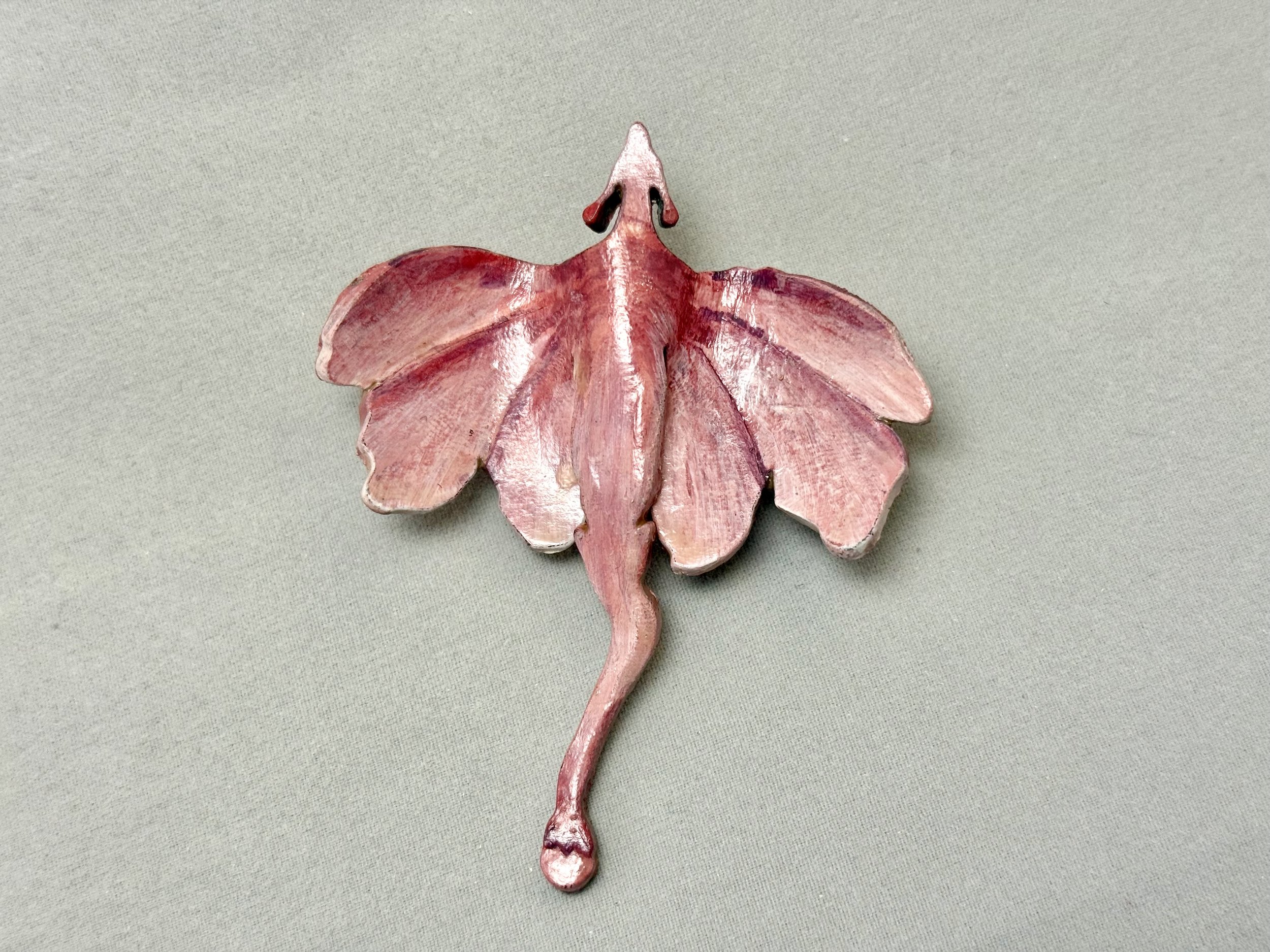 A small pink leather dragon in the design of a cherry blossom bloom by artist Bailey Maier