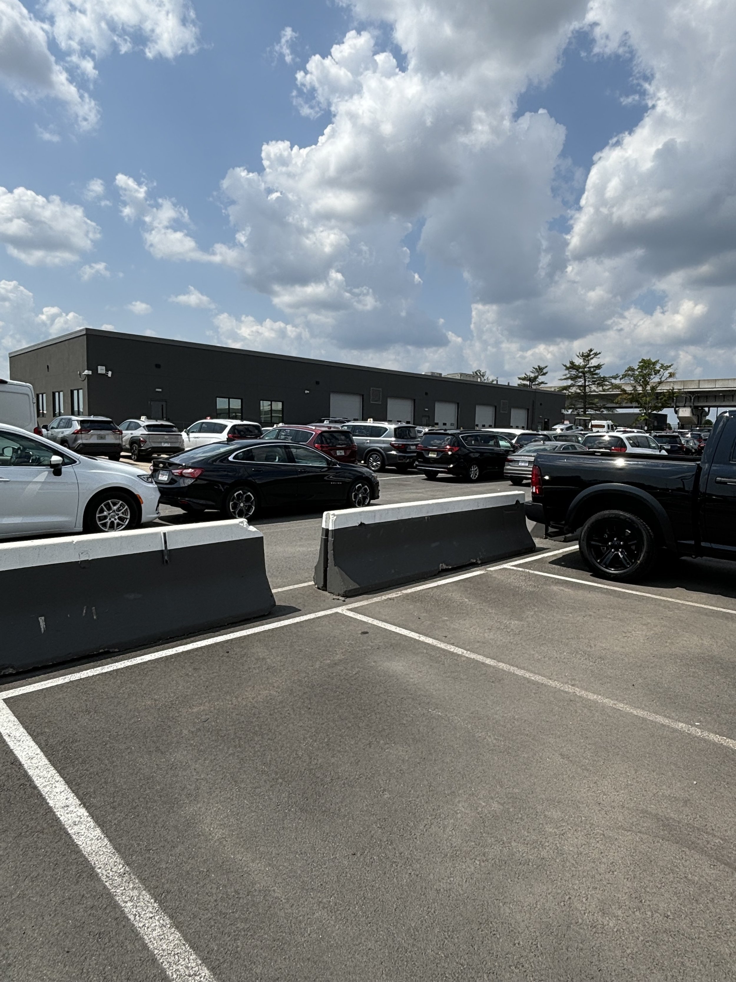 THE DARK GREY BUILDING WHICH HAS MULTIPLE VEHICLE BAYS AND NO COMPANY NAME. THE BUILDING IS FACELESS