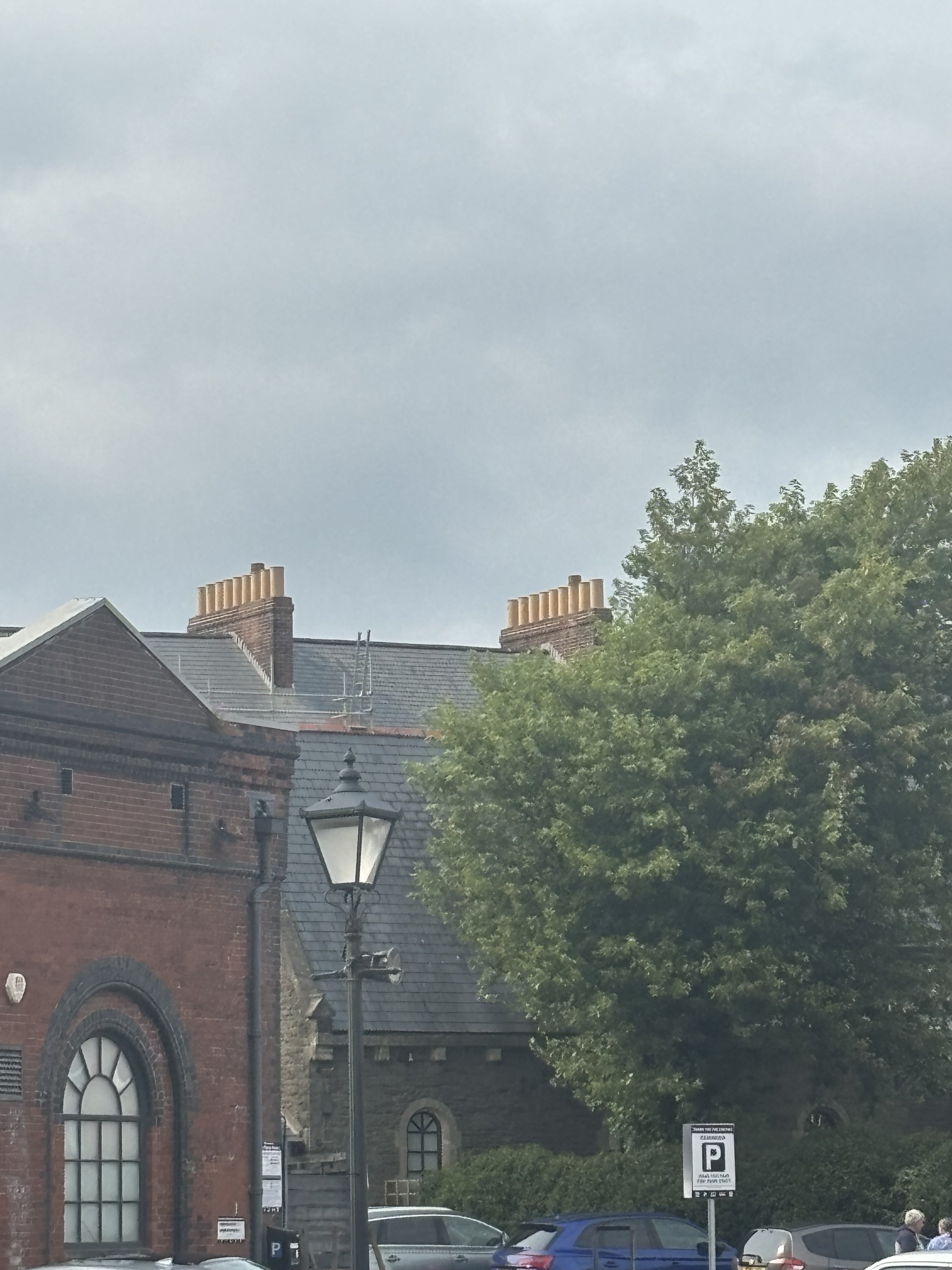 AN INTERESTING BUILDING IN THE BACKGROUND WITH 18 CHIMNEYS IN TOTAL. THIS IS A HUGE NUMBER OF CHIMNEYS AND WHY DO THEY NEED SO MANY? COULD IT BE FOR INCINURATOR PURPOSES?