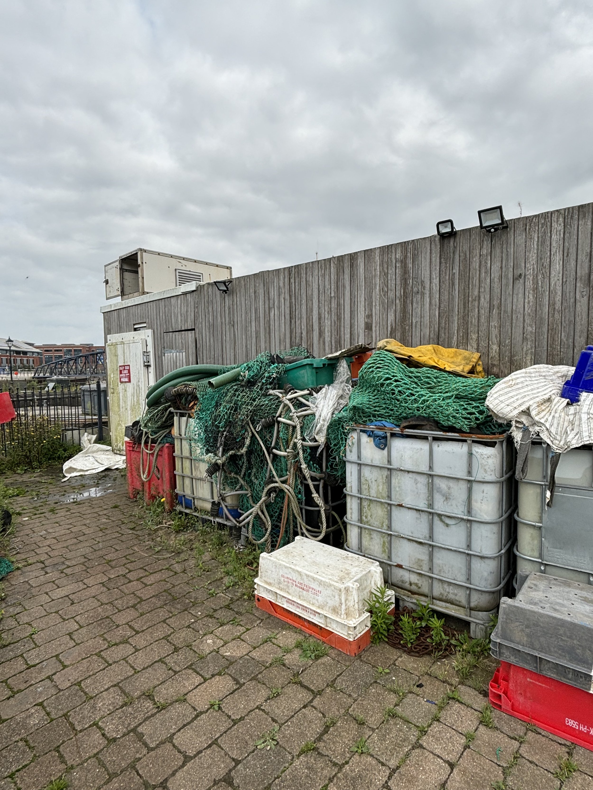 ANOTHER VIEW OF THE SAME AREA WITH LOTS OF MISDIRECTION. MOULDY DOOR TO PUT PEOPLE OFF. WHATS BEHIND THE FENCE AND WHATS THE CONTAINER ON TOP TO THE LEFT? WHAT’S INSIDE THOSE CAGED PLASTIC CONTAINERS? COULD IT BE THE LIQUIFIED WATER WHICH CONTAINS HU