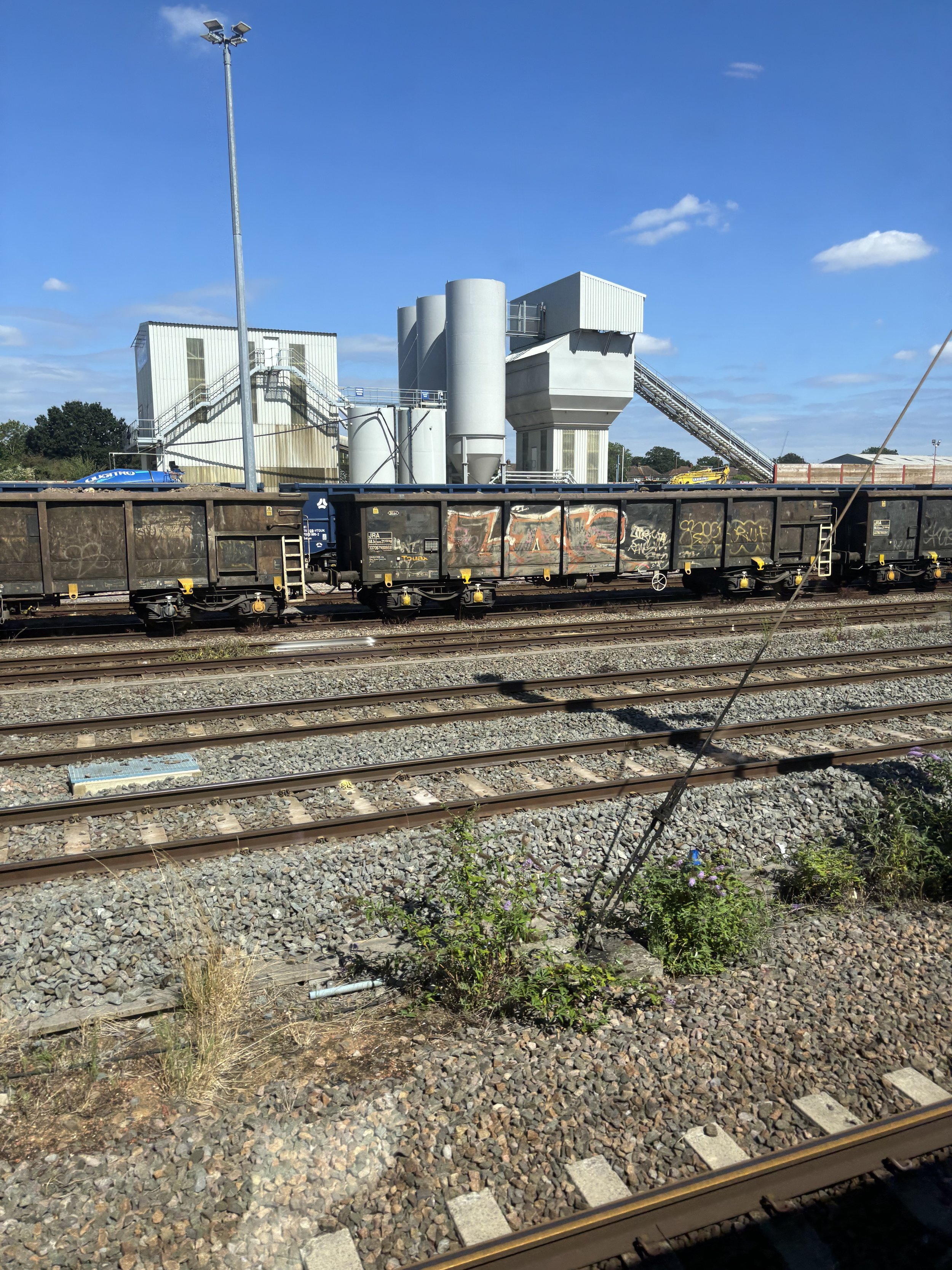 SLOUGH. MORE HUGH CHIMNEYS AND WHAT SEEMS TO BE A PRODUCTION LINE AND ALSO HIDDEN AT THE VERY FRONT BY ROLLING STOCK