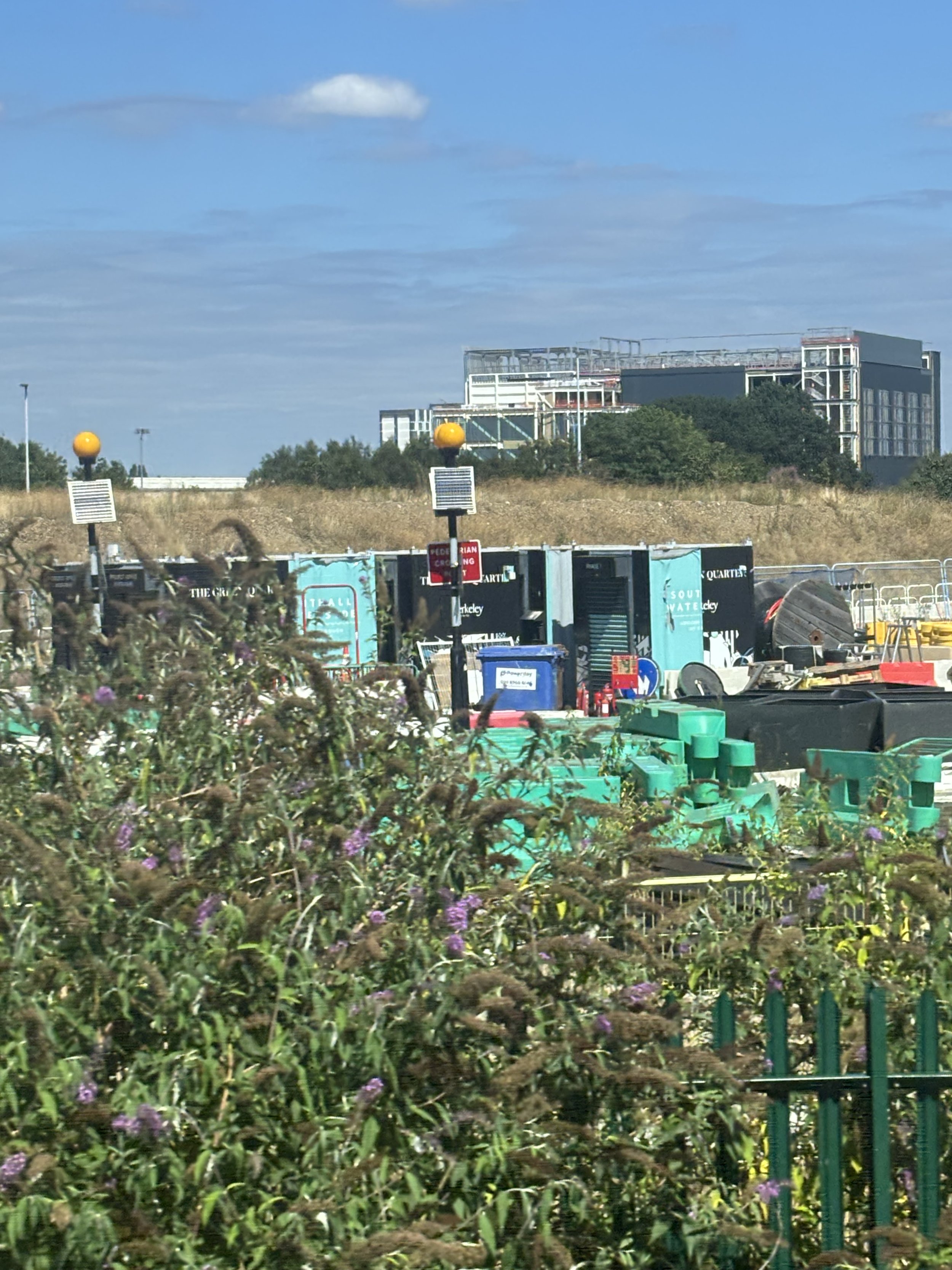 SLOUGH. A LOT OF DIFFERENT COLOURS IN THE FOREGROUND (MISDIRECTION) AND THEN WHAT SEEMS TO BE A HUGE AQUAMATION FACILITY IN THE BACKGROUND