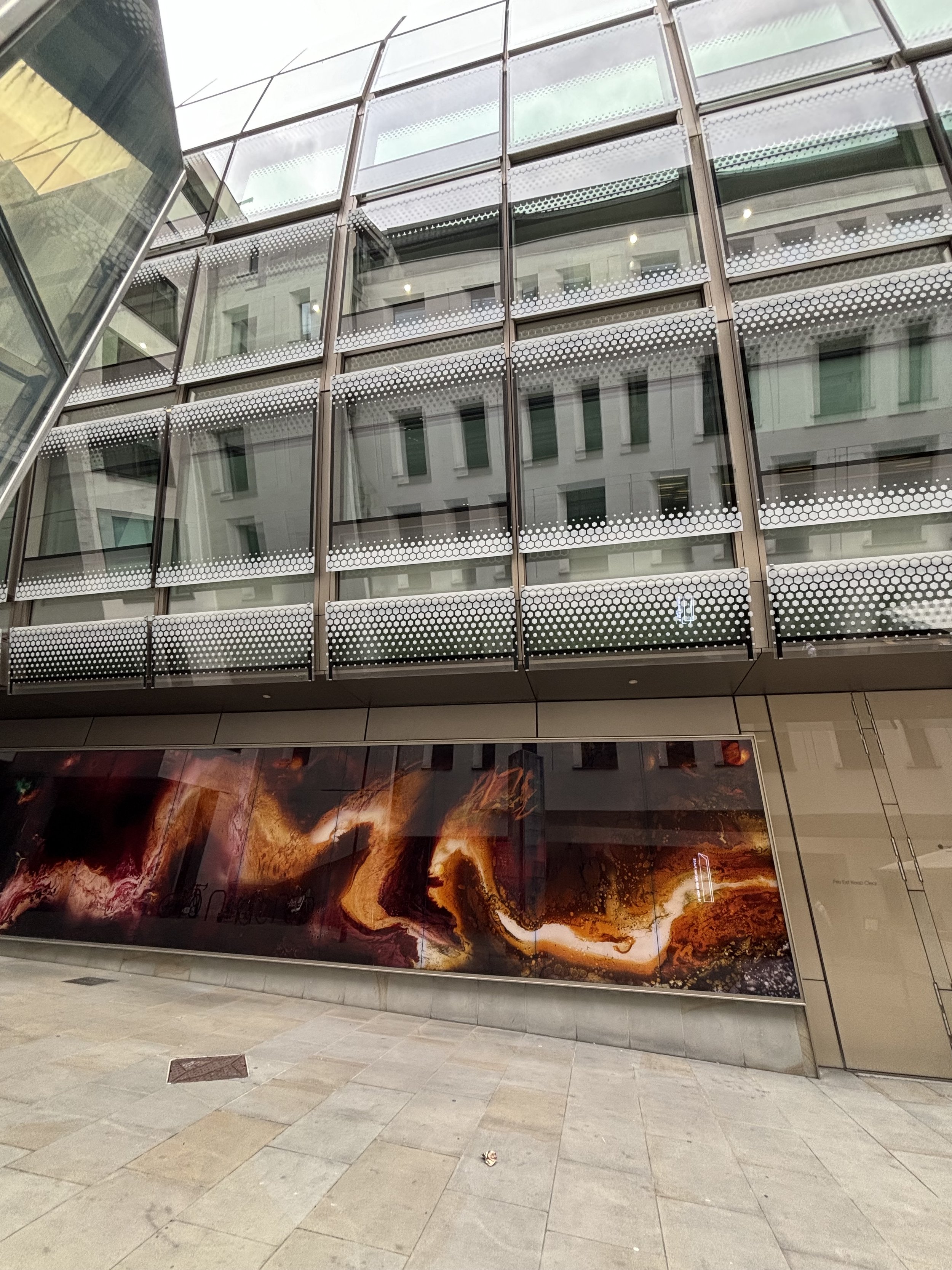 OXFORD STREET. JUST OFF OXFORD STREET INTO A SMALL SIDE STREET THERE'S A STRANGE BUILDING WITH LONG HORIZONTAL WINDOWS WITH FLAMES OF FIRE AND DUE TO THE UPWARDS BEND OF THE GLASS - YOU CANNOT SEE ANYTHING INSIDE. VERY GENERIC (LIKE NEW YORK) IN ITS