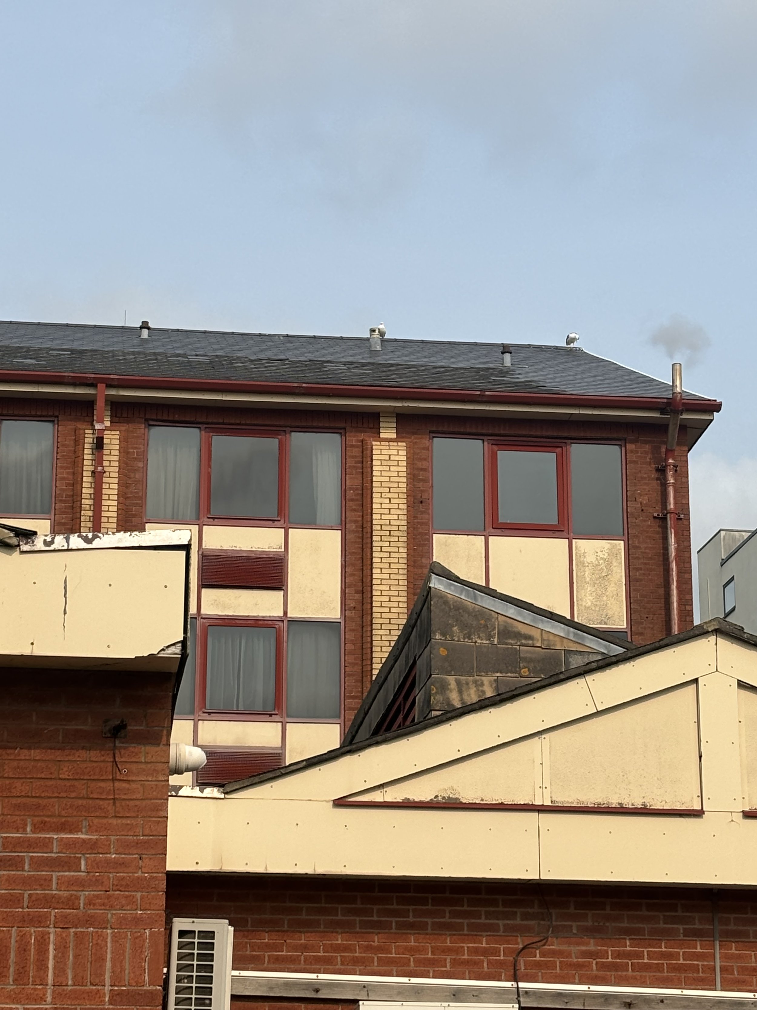 MARRIOT SWANSEA. LOTS OF CHIMNEY ON THE ROOF (AND RIGHT SIDE), SAME TRIANGULAR ROOFS, A WHITE PIPE TO THE LEFT AND A LARGE VENTILATOR IN THE MIDDLE AREA
