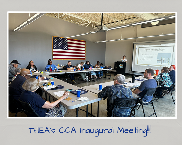 A group of people seated at tables in a conference room attending THEA's CCA inaugural meeting, with an American flag on the wall and a presentation projected on a screen.