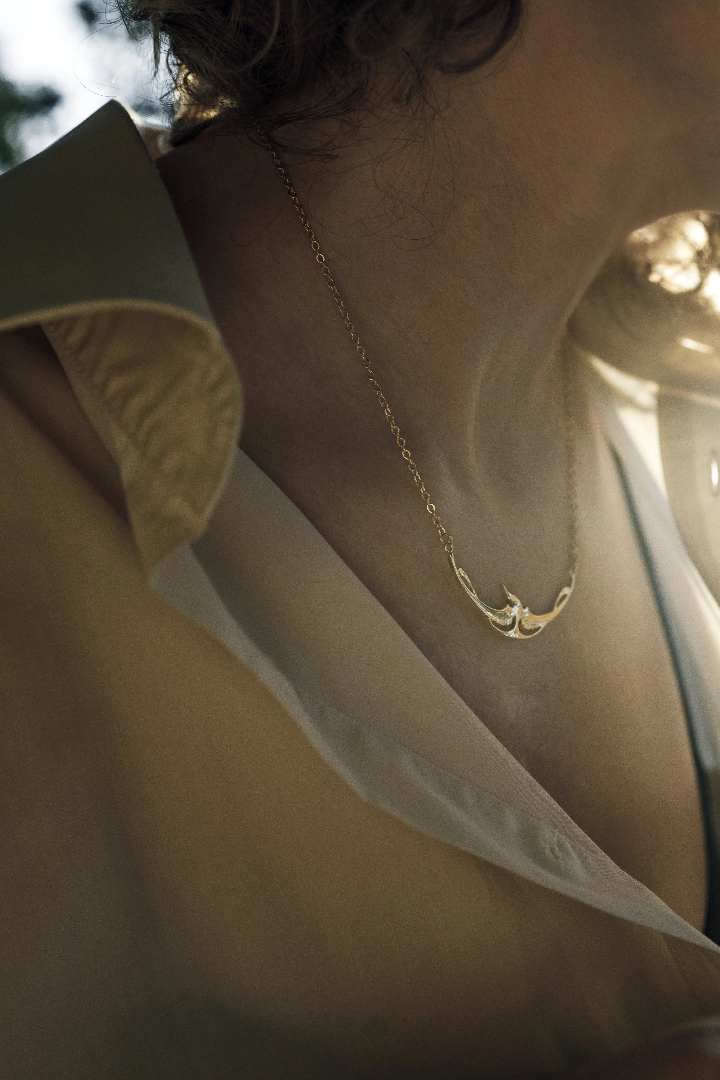 Collier cigogne doré porté sur le décolleté