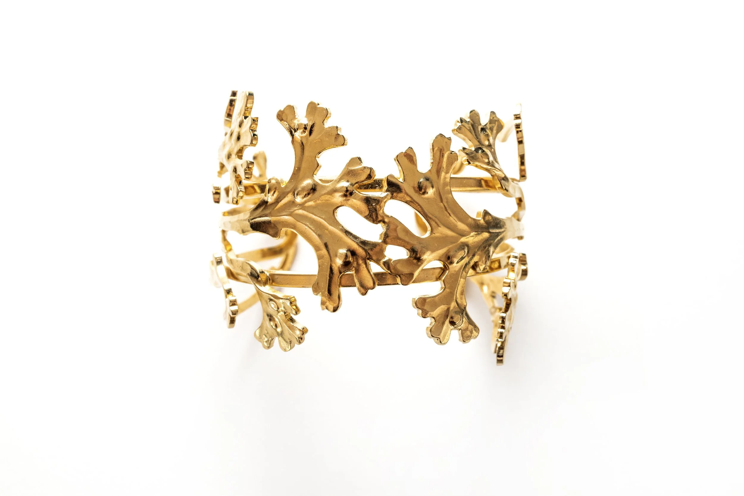 Gros plan sur le bracelet manchette corail, détail du motif et de la finition dorée
