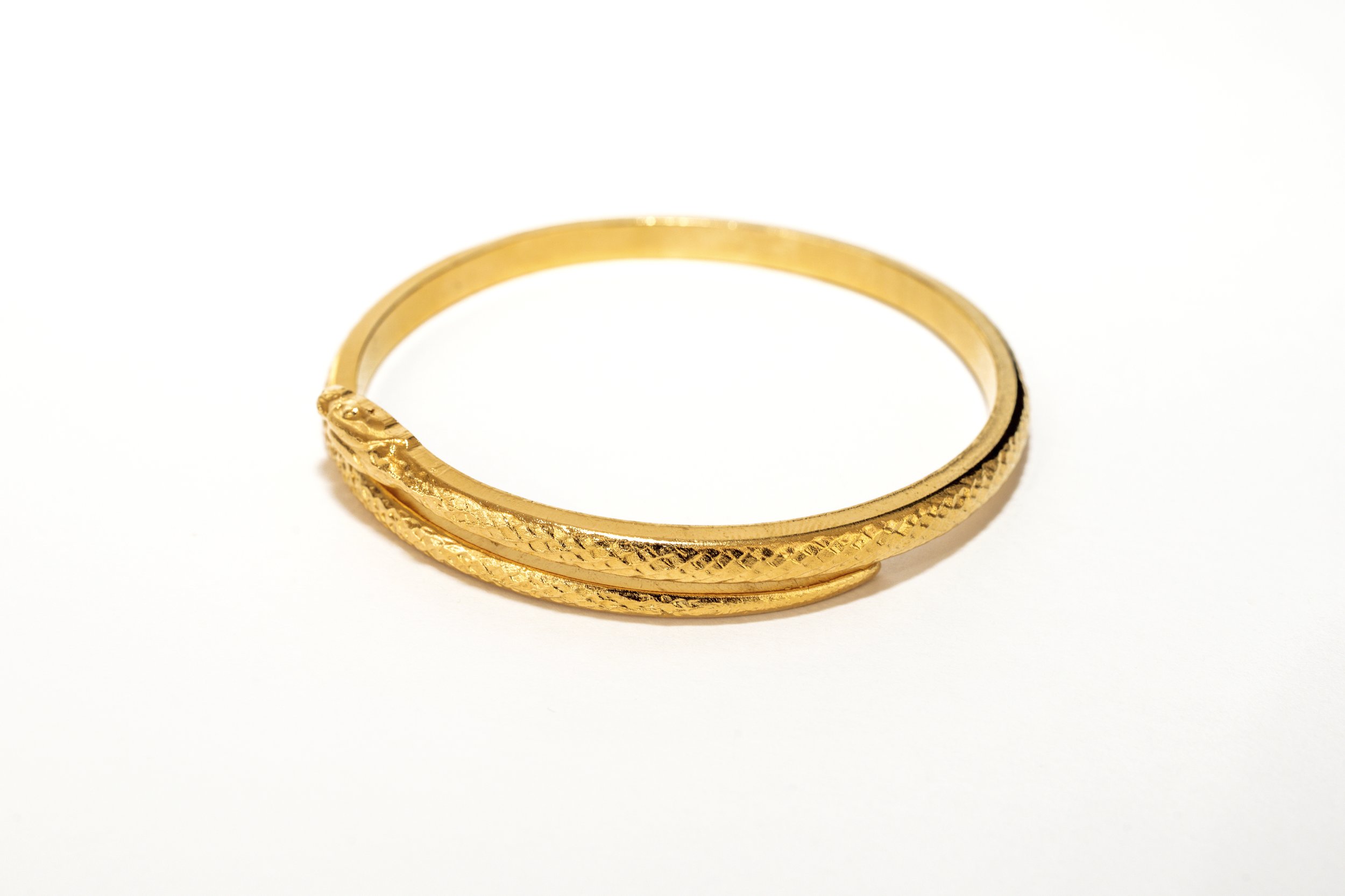 Gros plan sur le bracelet jonc serpent, détail du motif et de la finition dorée