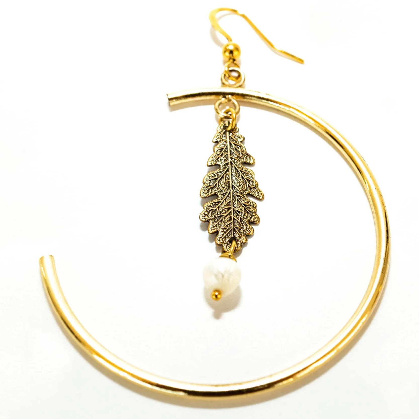 Gros plan sur les boucles d'oreilles créoles feuilles de chêne à perles, détail du motif et de la finition dorée