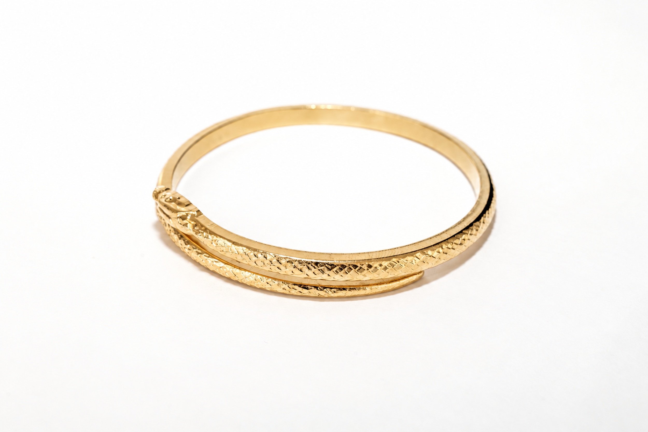 Close-up of the snake-inspired bangle, showing the pattern and gold finish