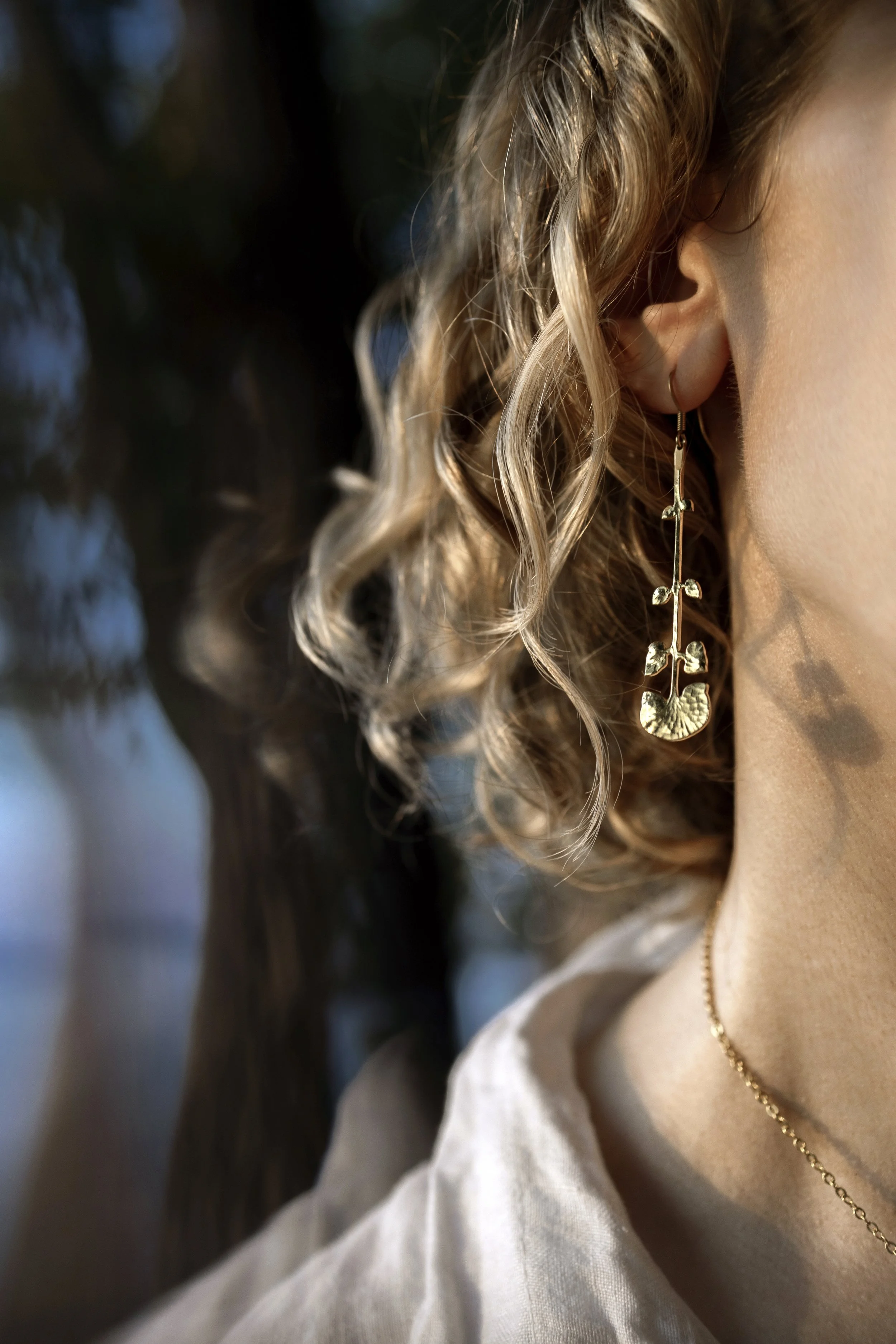 Gros plan sur les boucles d'oreilles gingko, détail du motif et de la finition dorée
