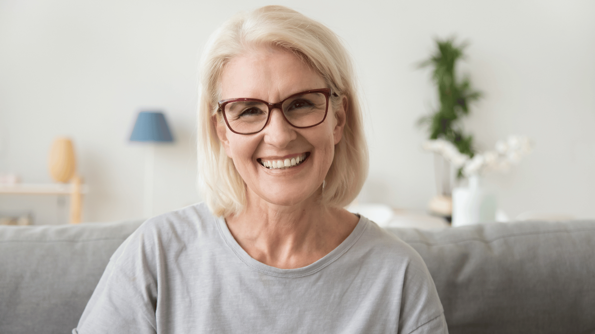 Older lady with blonde hair and glasses smile at camera