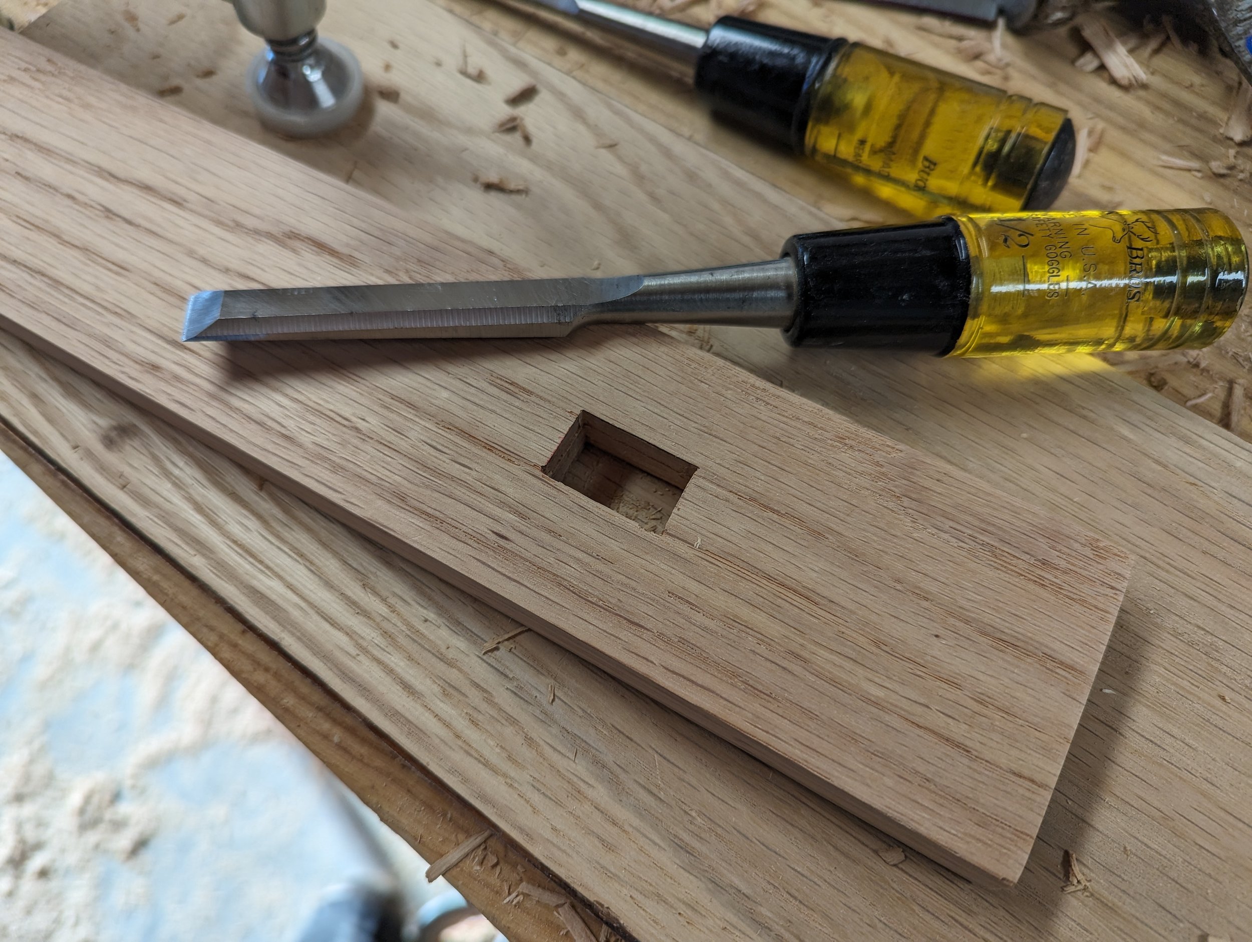  Two mortises were cut in each leg to insert the top and bottom cross members. A Forstner bit was used to drill out most of the mortise, while a chisel was used to cut out the remaining material. 