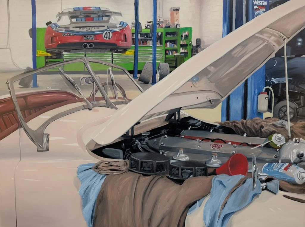 Image of an automotive shop showing a white Jaguar XK120 and a Porsche GT3 with a Martini livery.