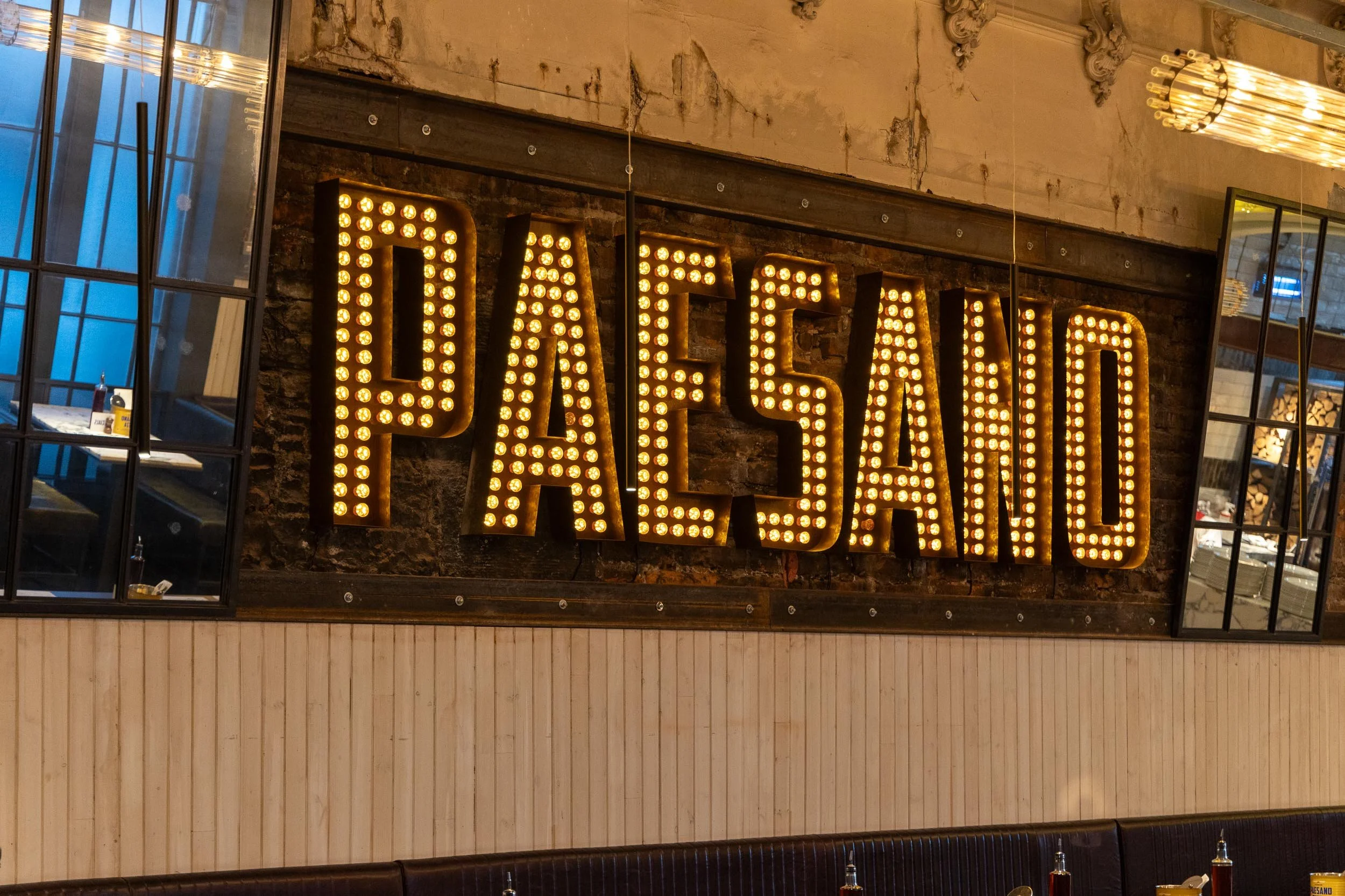 Decorative sign with the word 'PARSERIA' illuminated with multiple small light bulbs inside a restaurant or cafe.