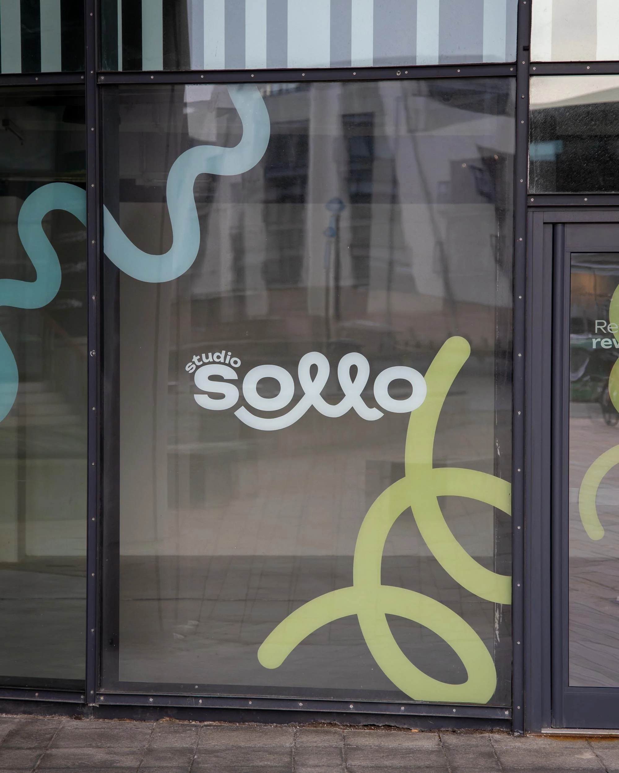 Glass window with the words "studio solo" and decorative squiggly lines in blue, green, and white.