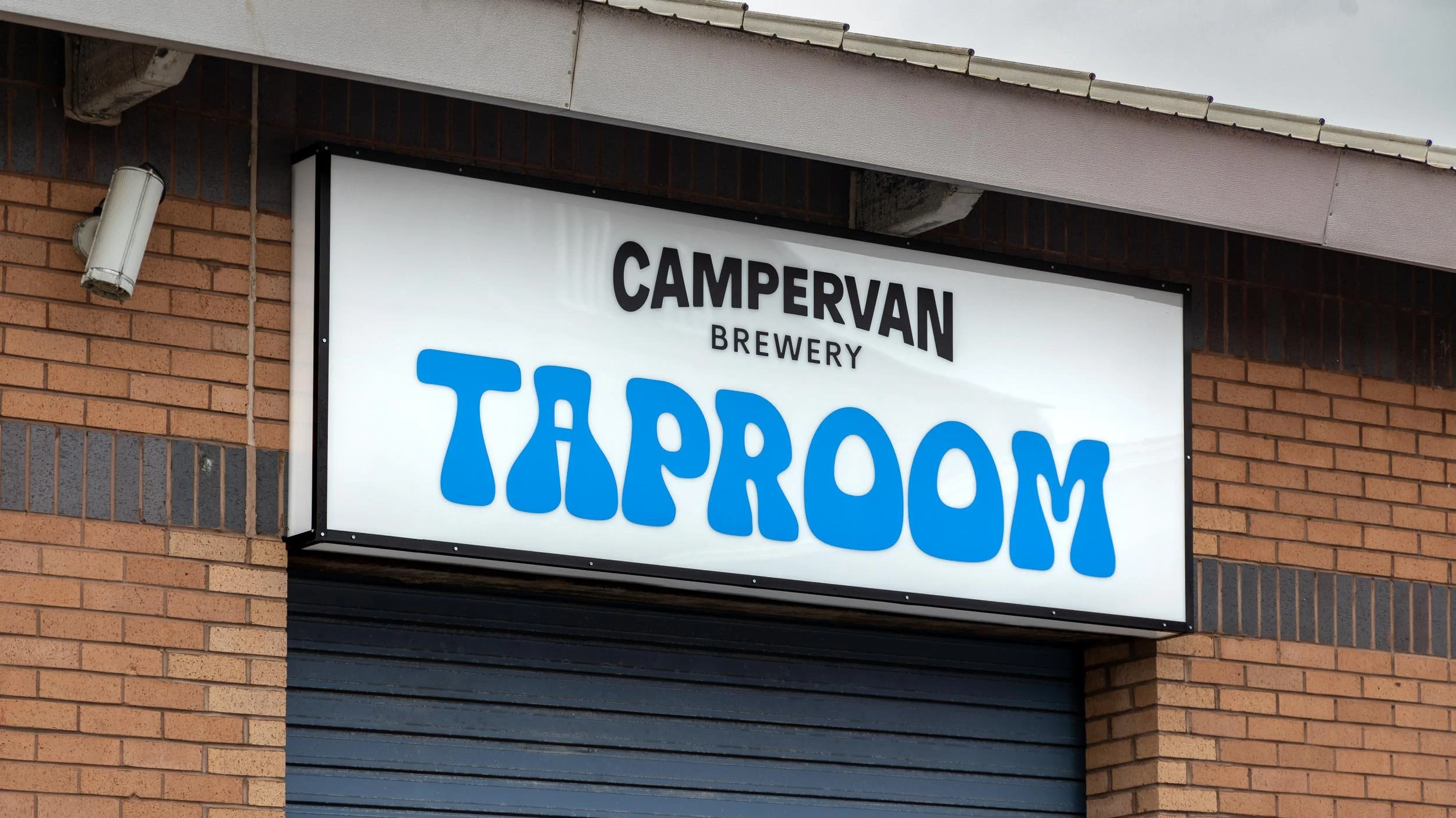 Signboard for Campervan Brewery Taproom on brick building.