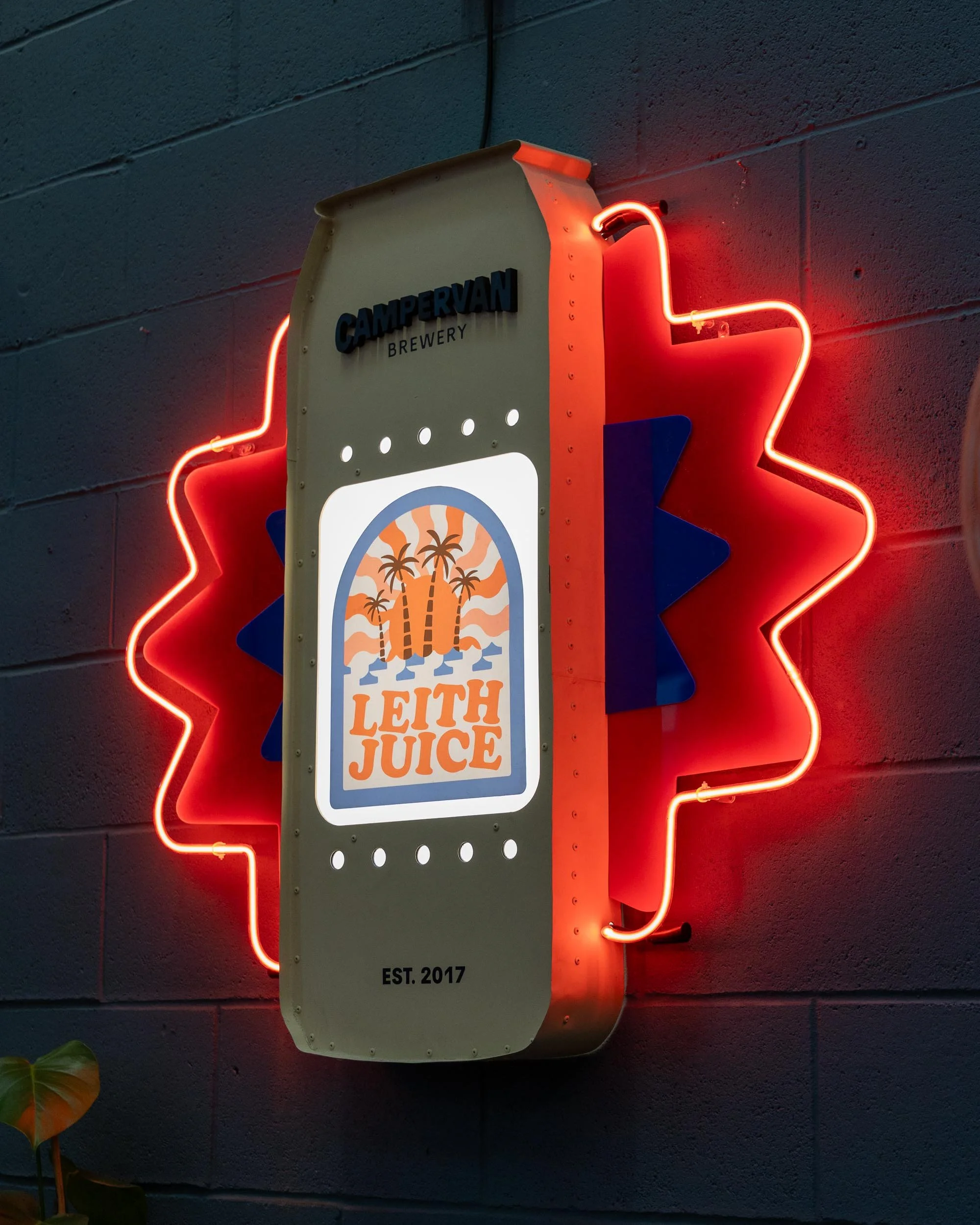 Neon sign shaped like a beverage can with the text 'Leith Juice,' 'Campervan Brewery,' and 'Est. 2017,' on a dark wall, with a red neon outline around the can.