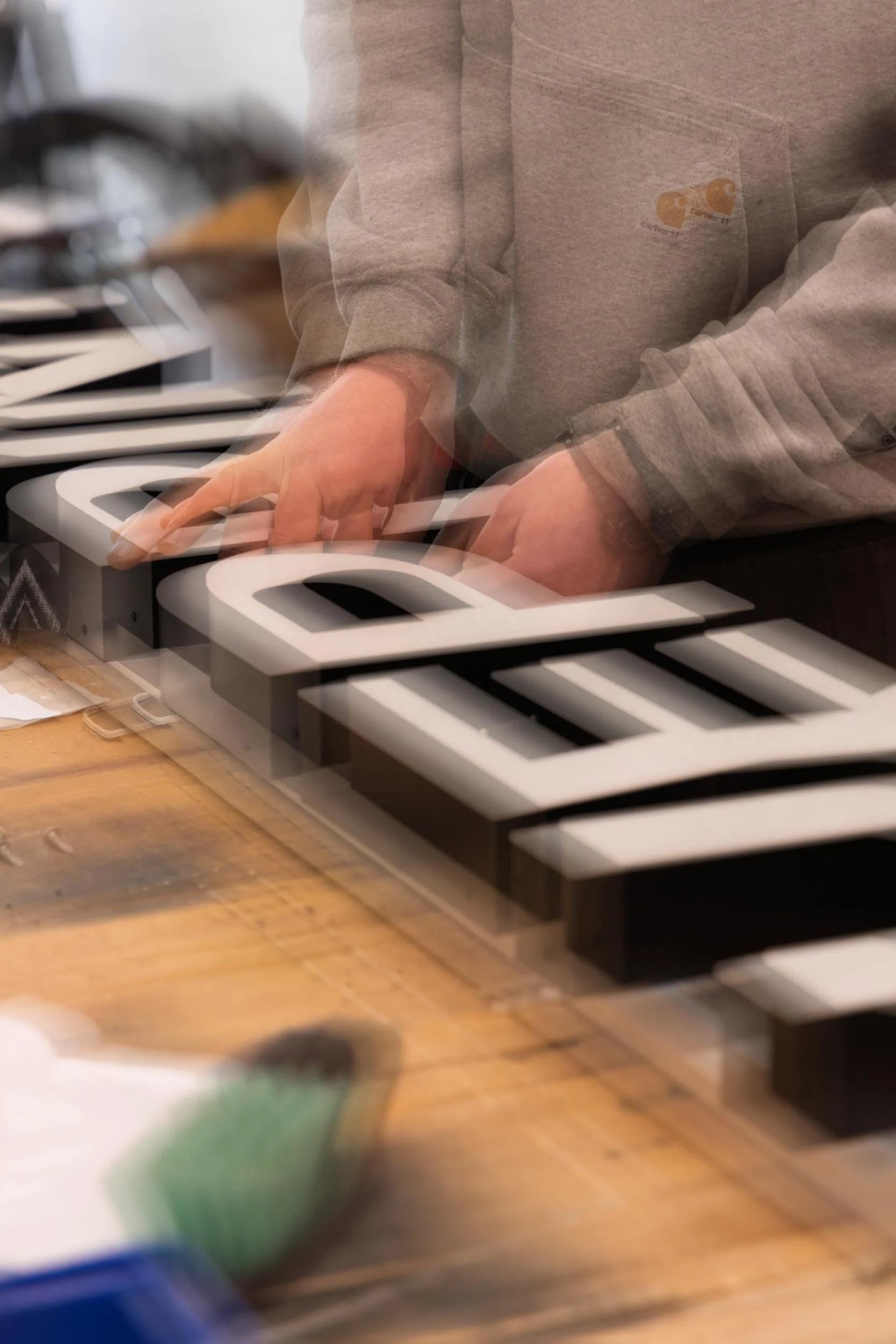 Person playing a keyboard with blurred background of a wooden table and other objects.