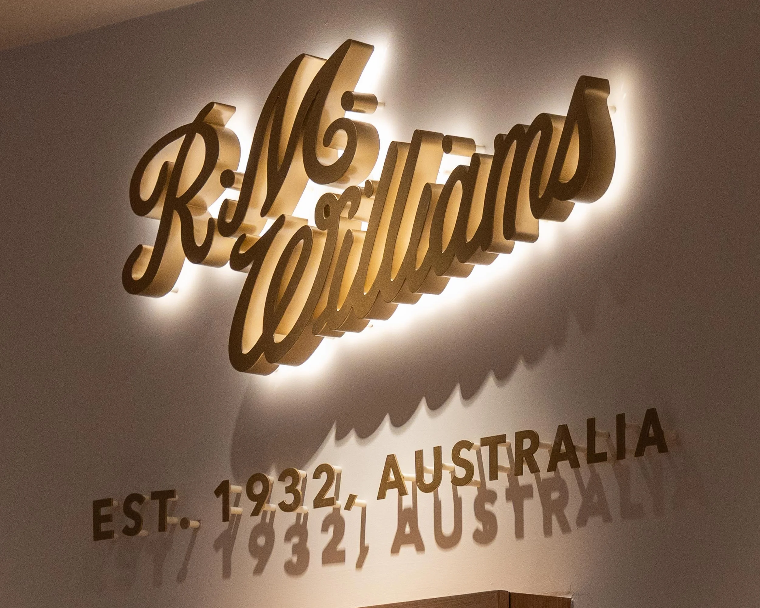 Backlit 3D wall sign with the words 'R.M.Williams' in cursive script and 'EST. 1932, Australia' in metal flat cut letters underneath.