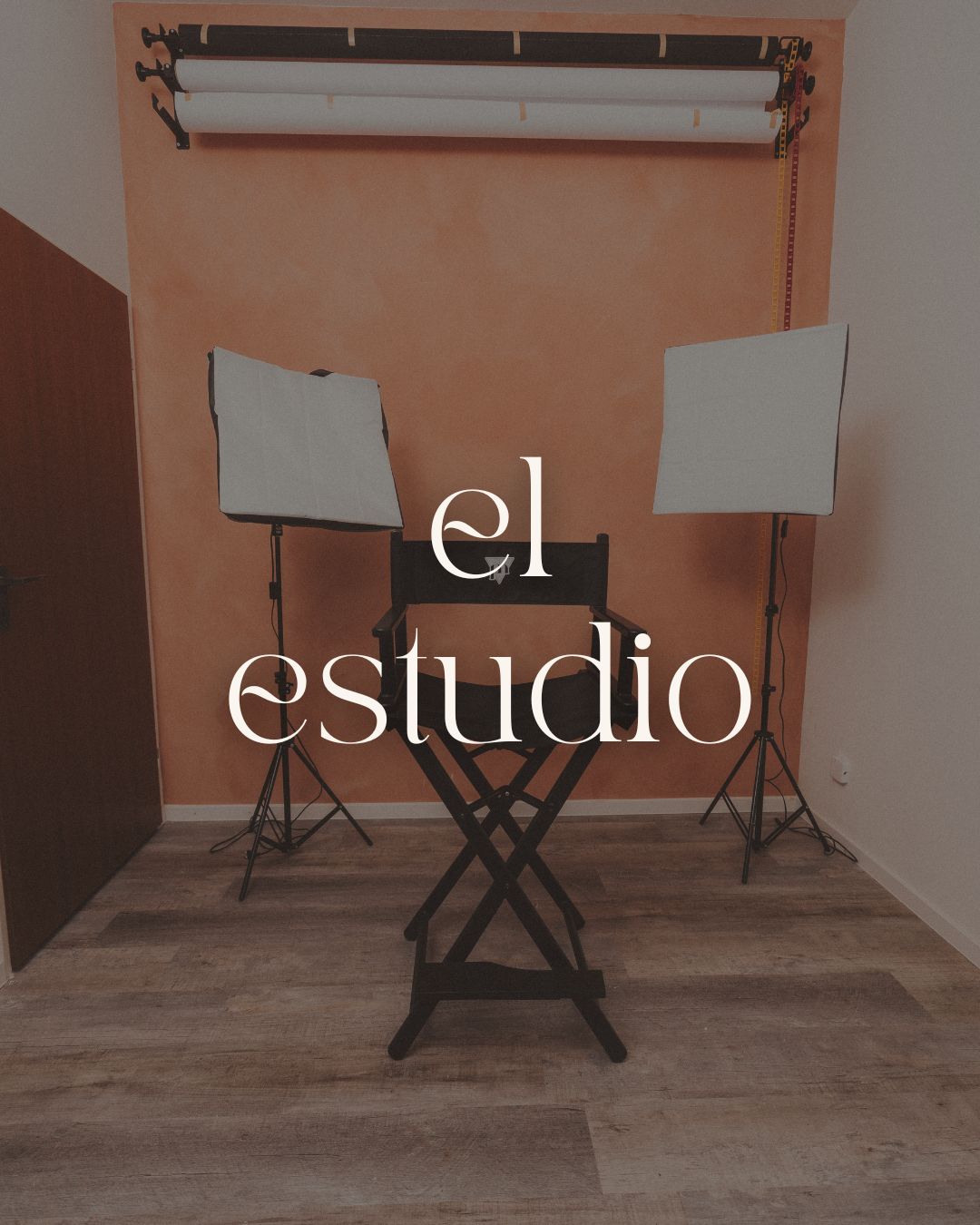 Photography studio setup with two softbox lights, a director's chair, a backdrop roller, and wooden flooring