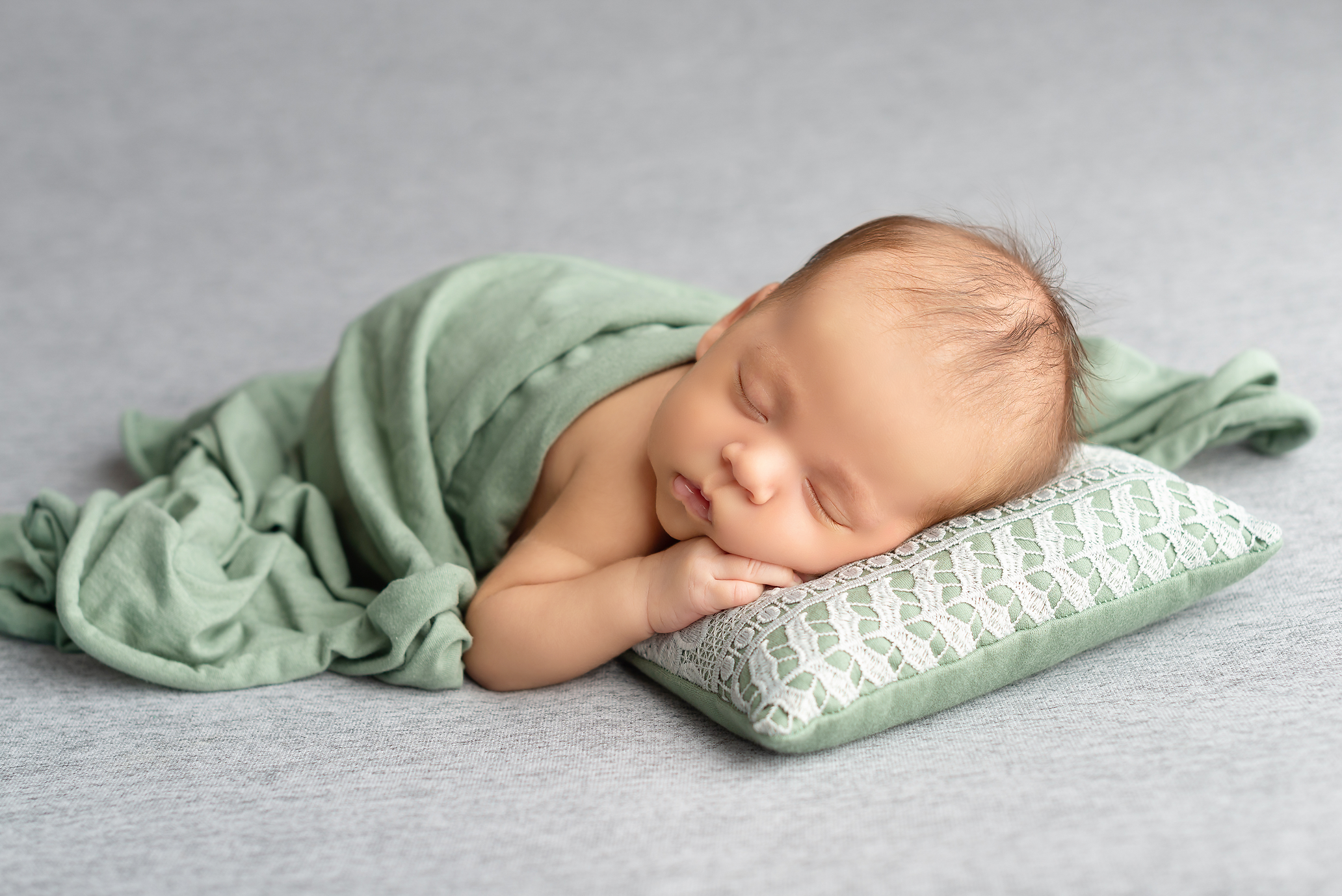 baby boy on grey blanket with green wrap and pillow in Kingston portrait studio