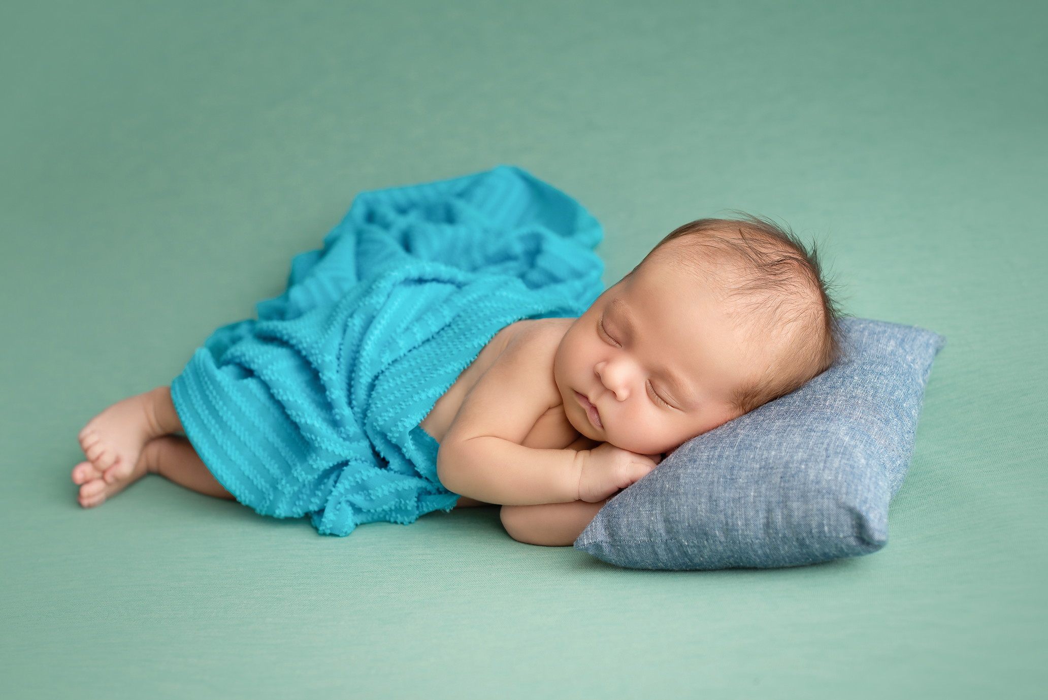 baby boy on green blanket with blue pillows in Kingston portrait studio