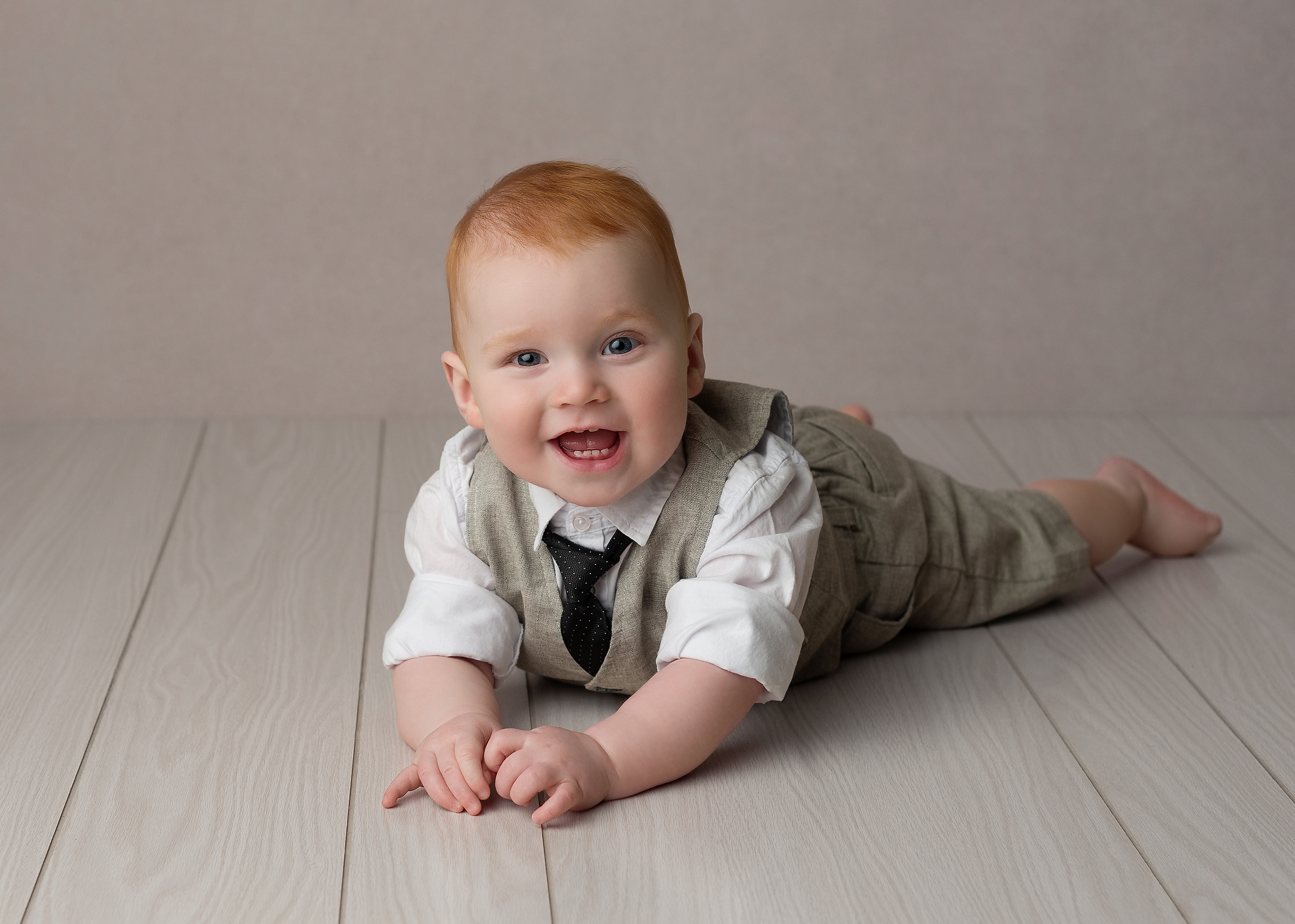 baby boy wearing a suit laying on his belly with red hair