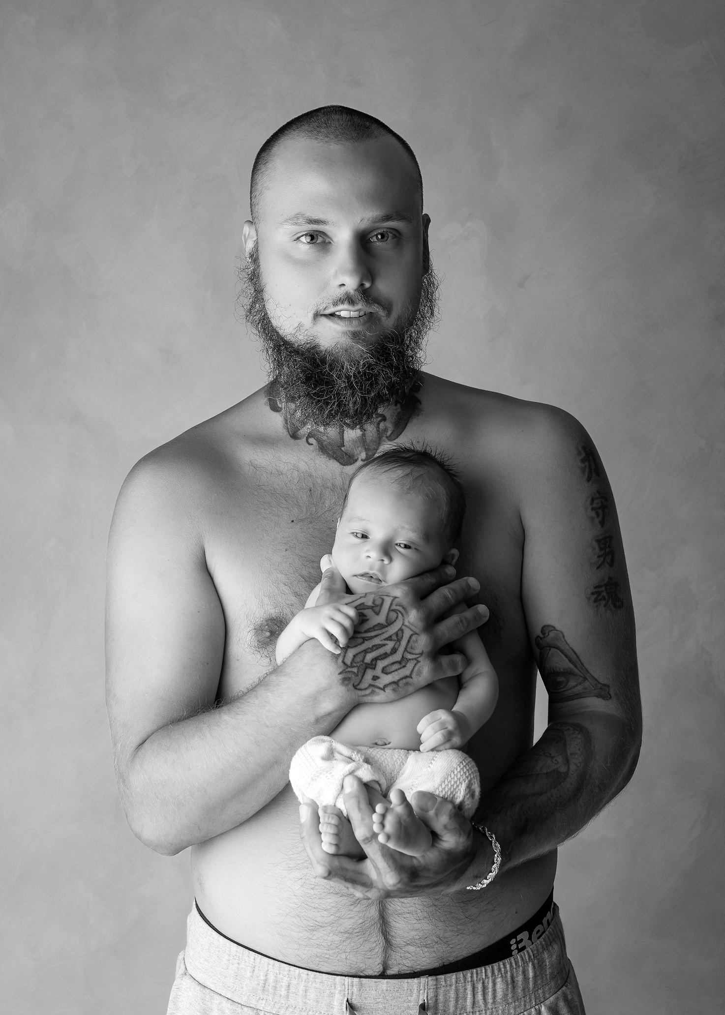 baby boy held in father's arms in black and white in Kingston portrait studio