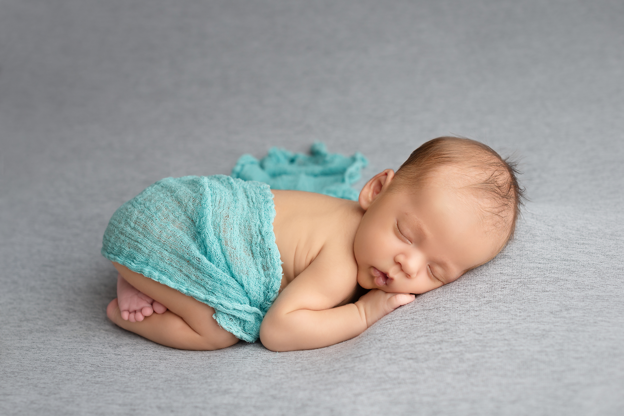 baby boy sleeping on grey blanket with teal wrap in Kingston portrait studio