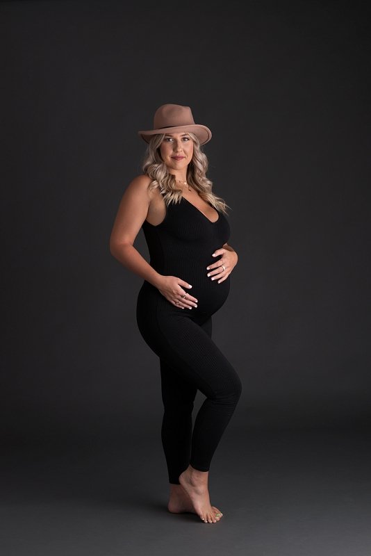 pregnant mother in black jumpsuit with a hat