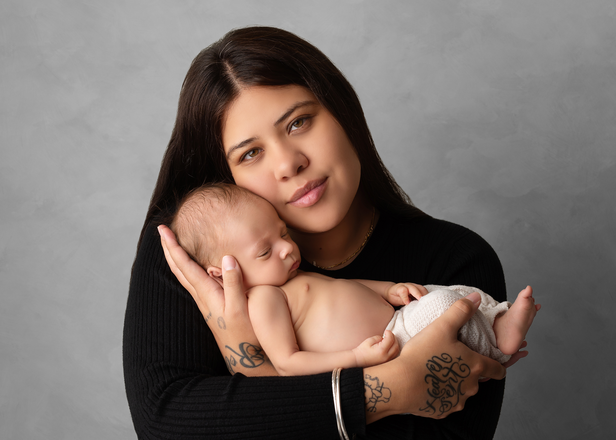 baby boy held in mother's arms with tattoos in Kingston portrait studio