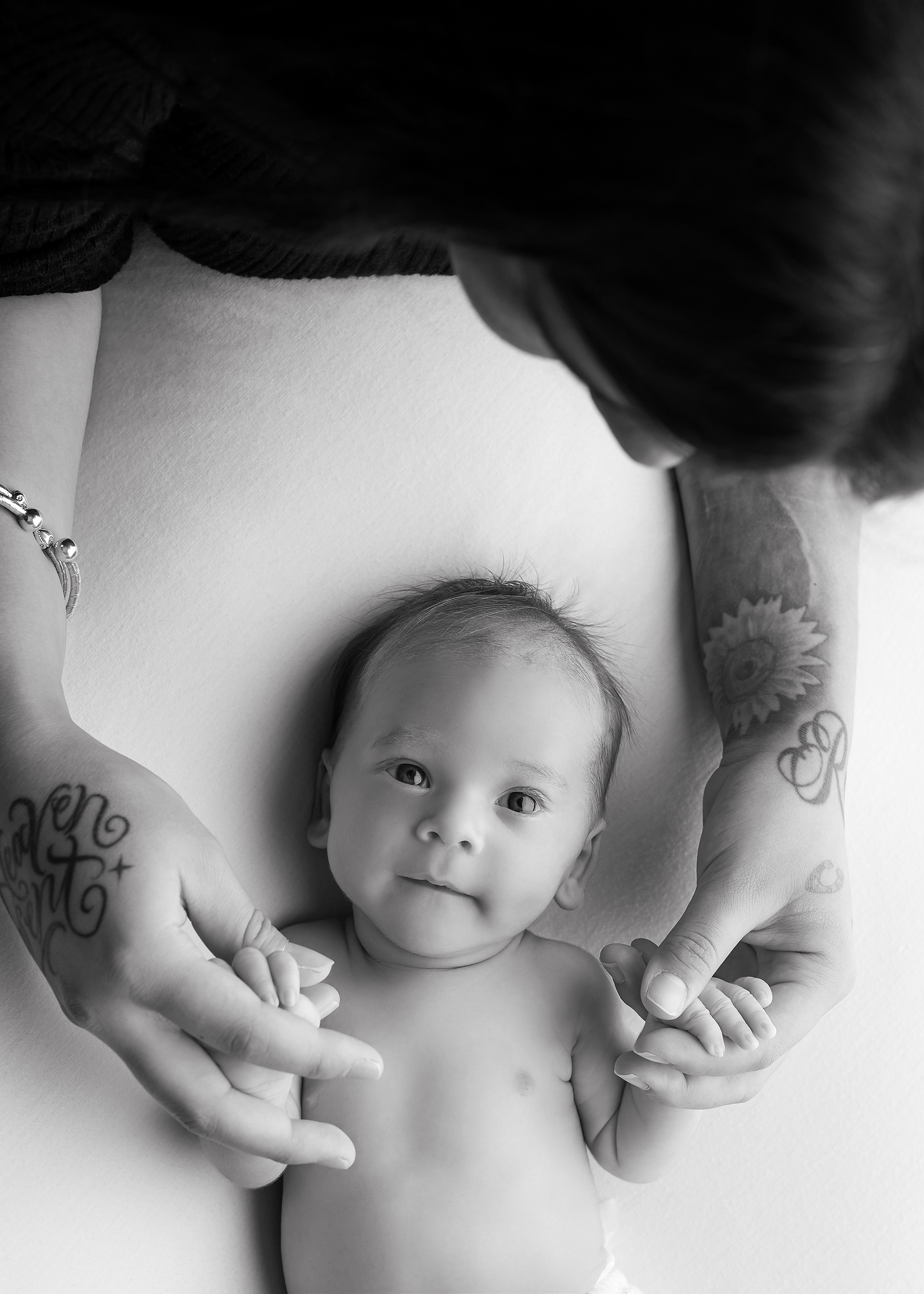 baby boy in black and white held in mother's hands in Kingston Portrait Studio
