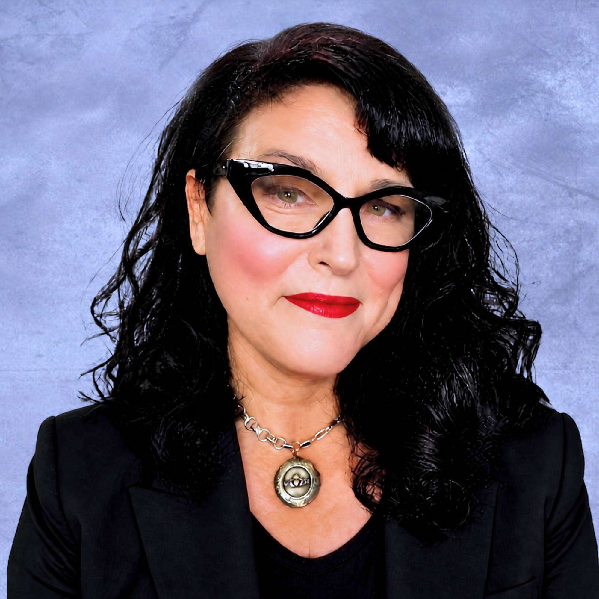Person with dark hair and red lipstick wearing a chain necklace.