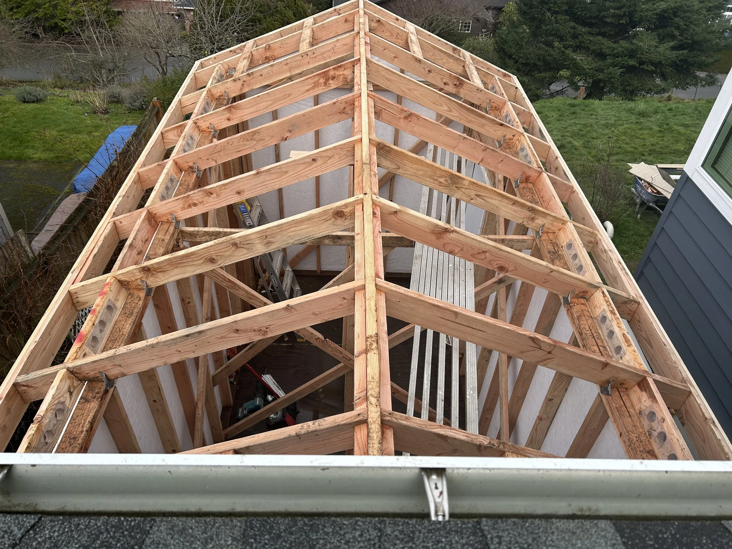 Wooden framing structure of a roof under construction, viewed from above.