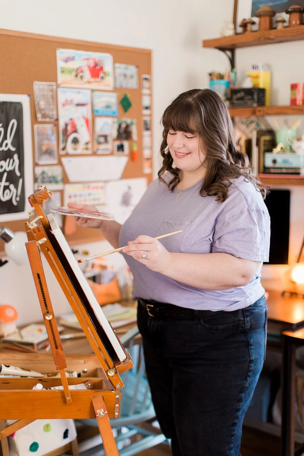 Artist holding a paint palette and painting on an easel