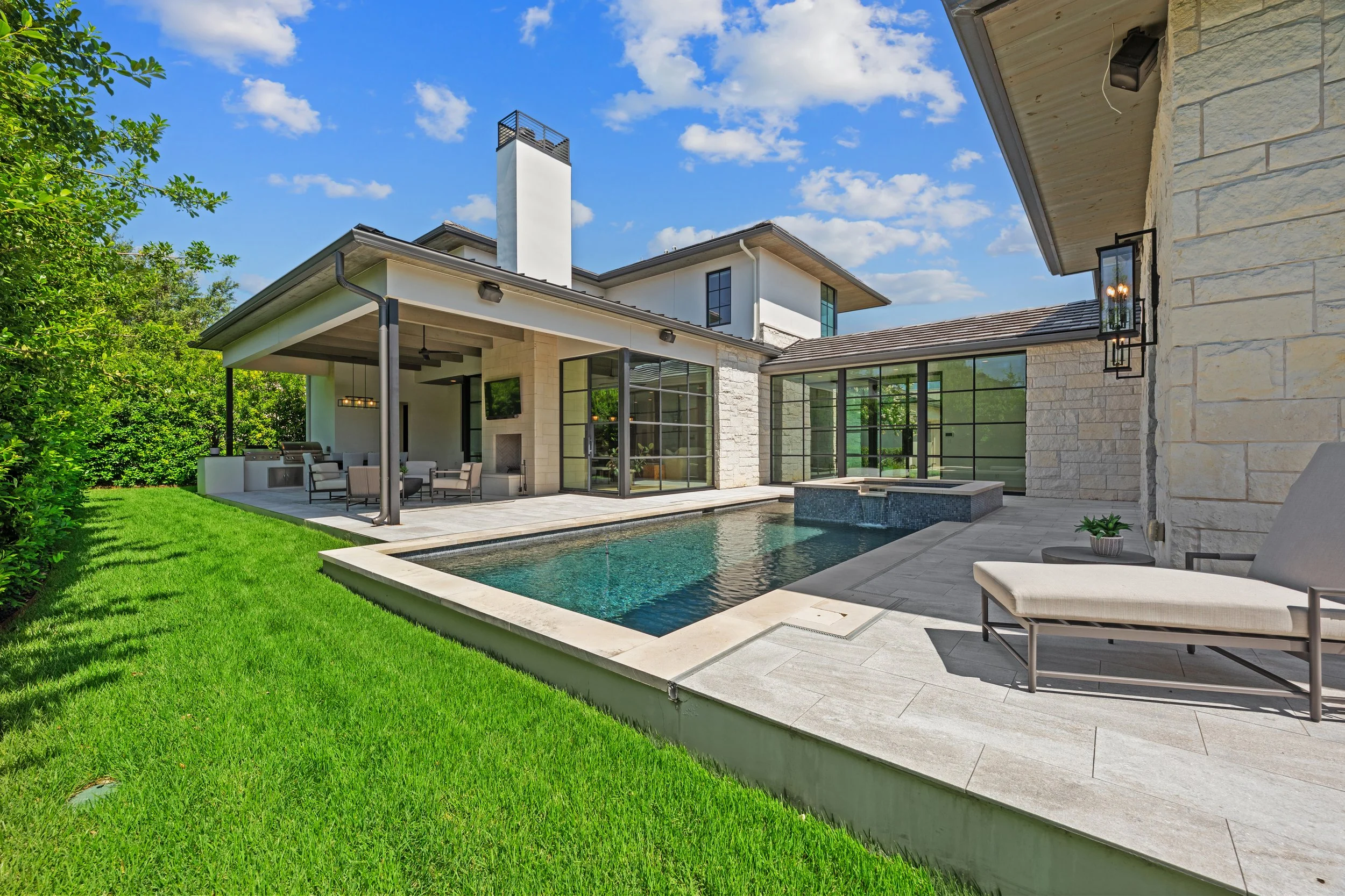 Exterior photo on a sunny day in Austin showcasing a beautiful pool and contemporary home