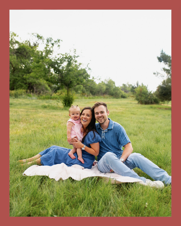 Family sitting on grass in a park, with a baby in Denver, Colorado.